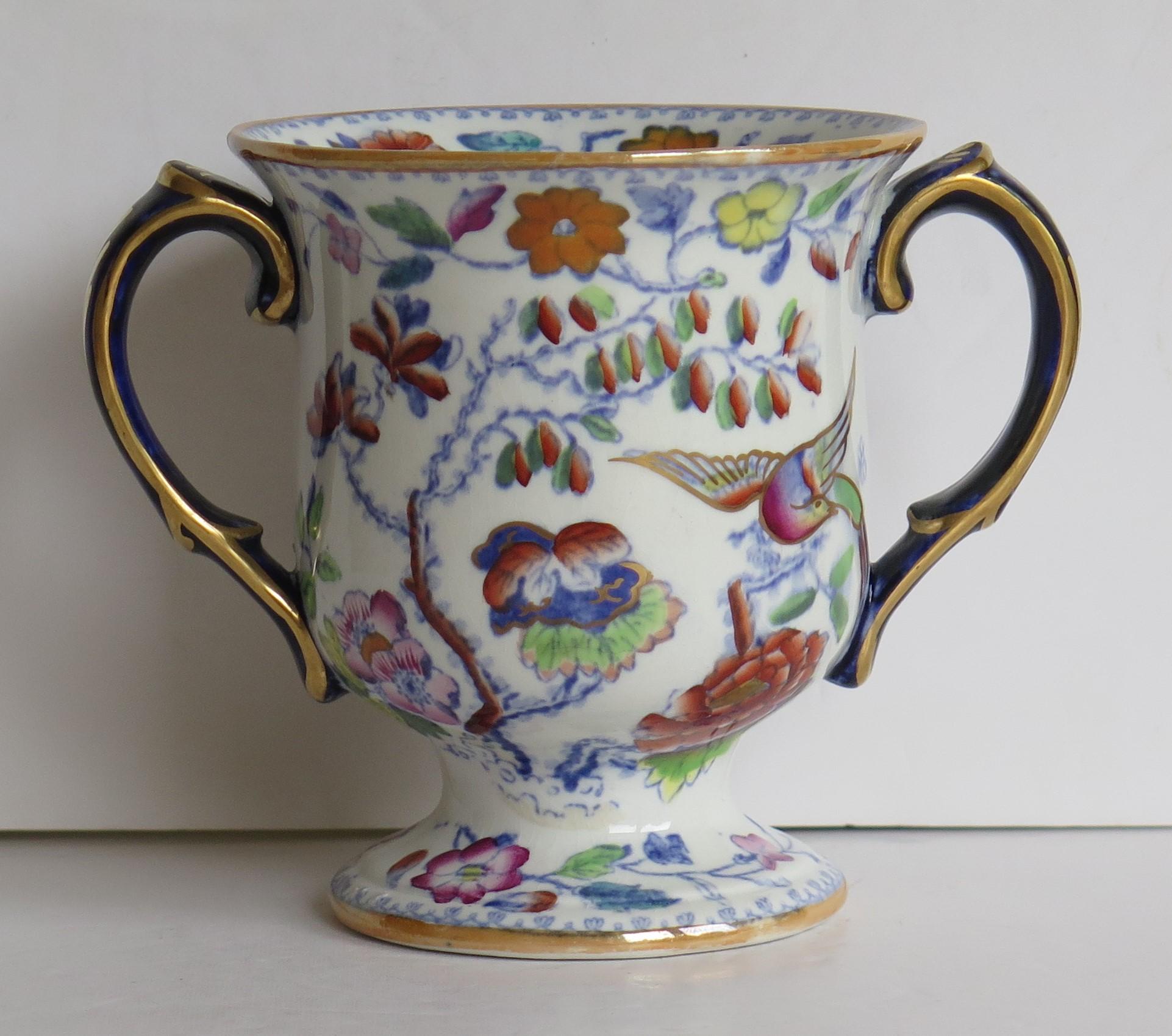 This is a rare ironstone twin handled loving cup or small vase in a rare shape, hand enameled & gilded in the Flying Bird pattern, made by Mason's Ironstone of Lane Delph, Staffordshire, England, during the 19th century, circa 1860.

This piece is