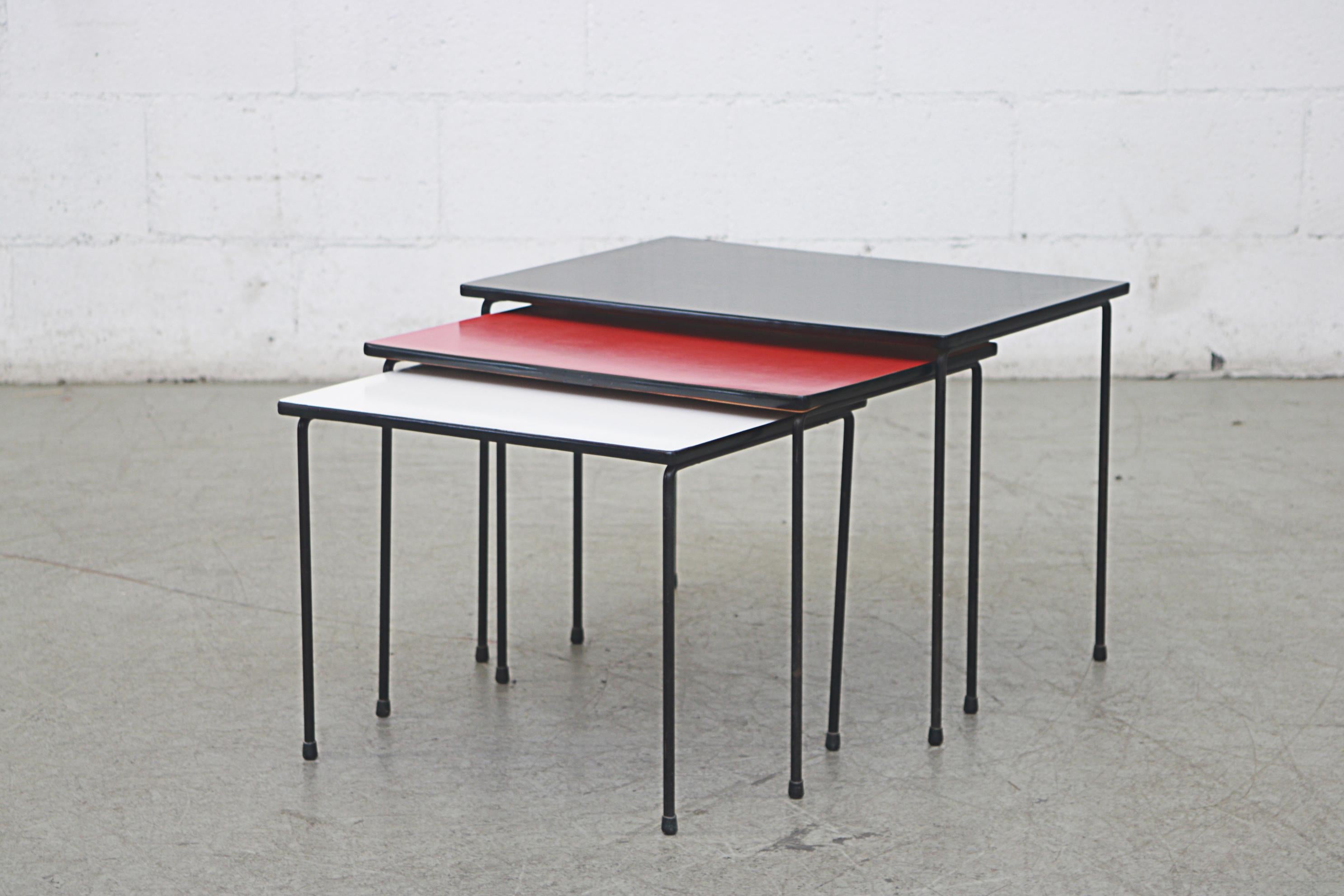 Pilastro Set of 3 mid-century multi-colored nesting tables. Black enameled metal frames and formica tops in black, red, and white. Original condition, with visible wear consistent with its age and usage. The dimensions are 21.75 x 15.5 x 15.5, 19.25