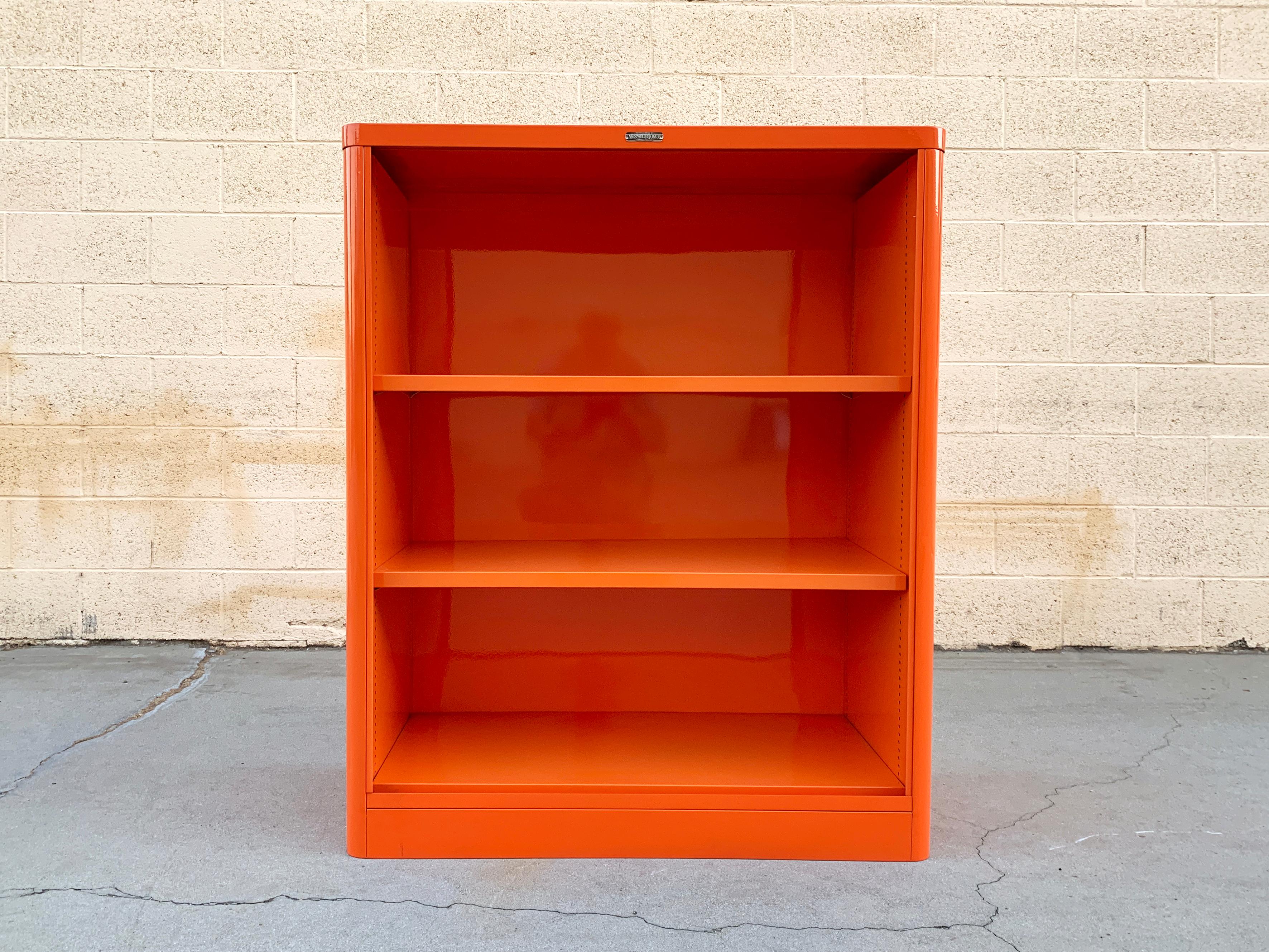 Uncommon McDowell Craig steel tanker bookcase refinished in a powder-coated pop of Tangerine (OG 05). Deeper than most tanker bookcases from this era, it features rounded corners, adjustable shelves and original McDowell Craig label. It's sleek and