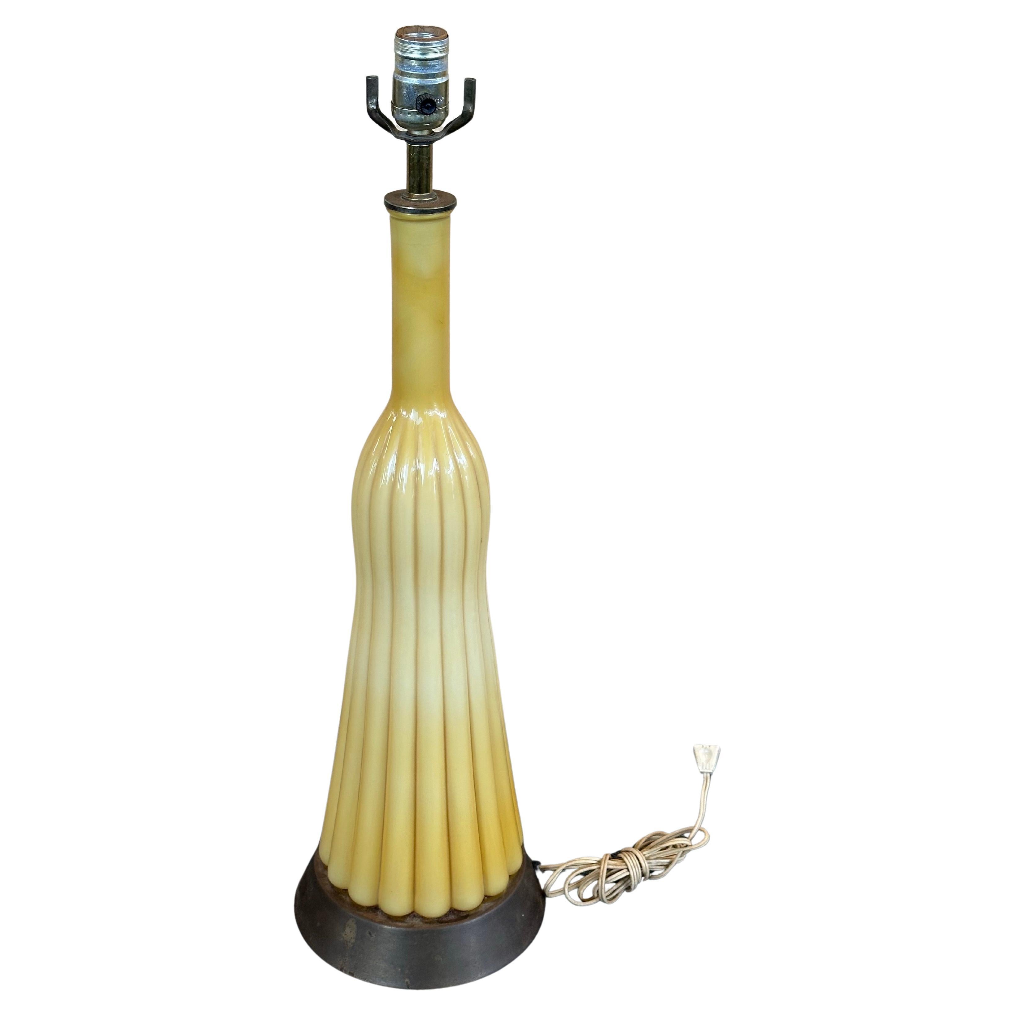 Rare MCM Empoli Butterscotch Ribbed Cased Murano Glass Table Lamp, circa 1960s. The gorgeous lamp sits on a bronze colored base with all working original wiring. The Lamp does not include a shade or harp, is in good vintage condition with no cracks