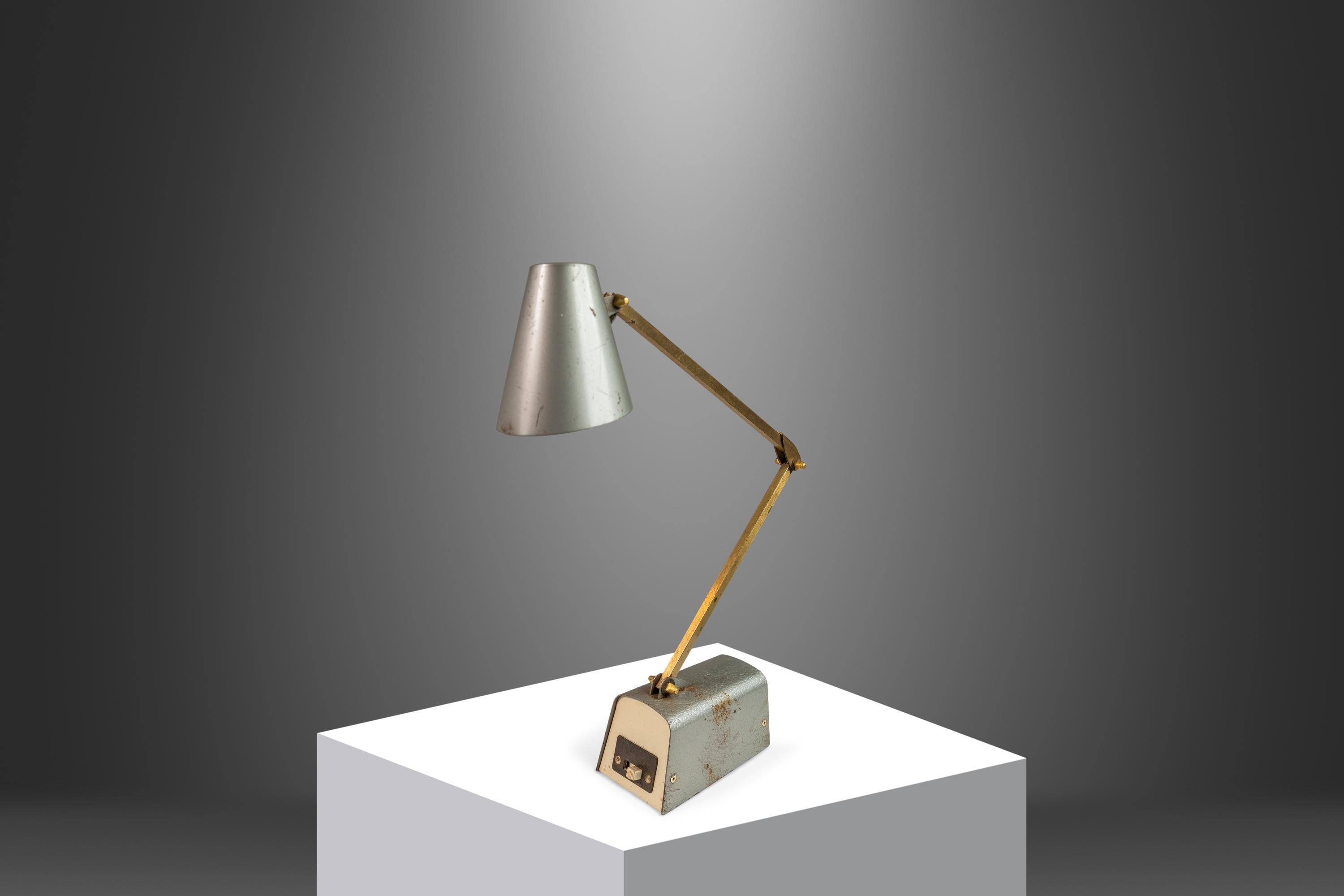 Introducing a rare, American-made industrial tensor desk lamp produced by Dazor in the mid-1960's. Made from a mix of American steel and solid brass this versatile lamp, though thoroughly patinaed, is ultra-functional. Featuring a high and low lamp