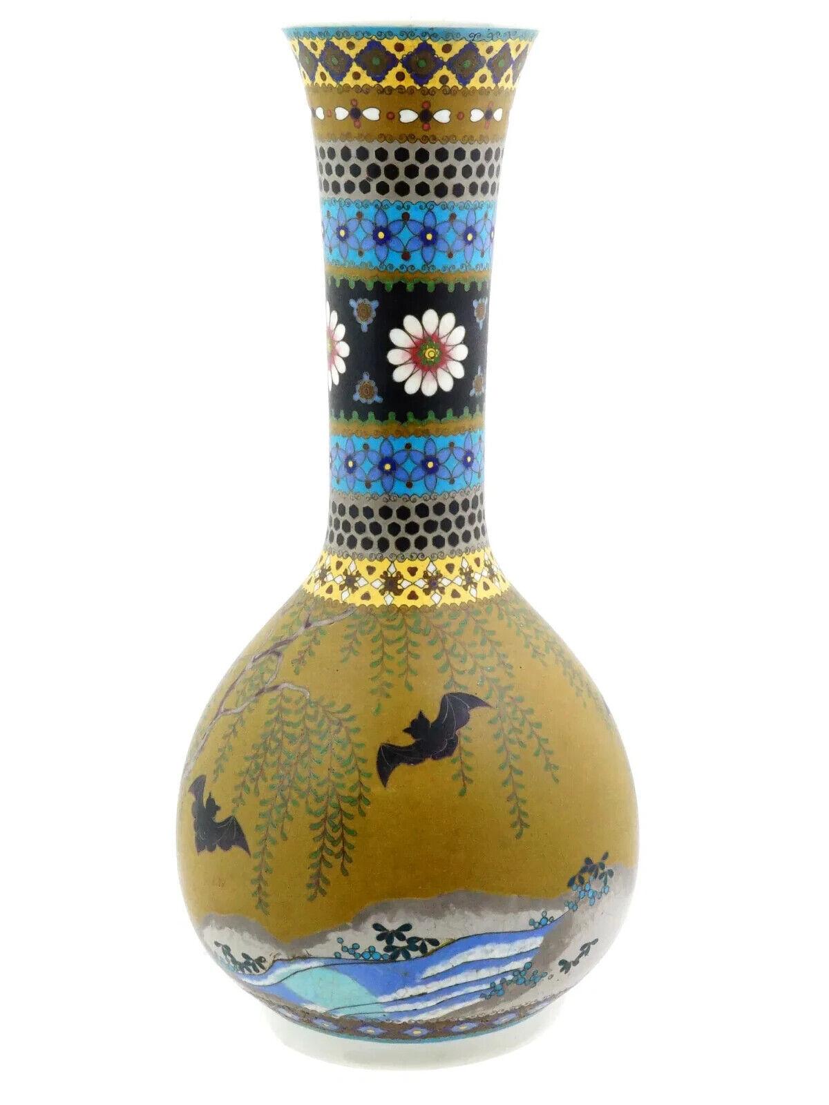 A Japanese enamel on porcelain vase. The vase has a globular shaped body and a narrow neck with a fluted mouth. The vase is enameled with a polychrome design representing a river landscape view with flying bats made in the Cloisonne technique. The