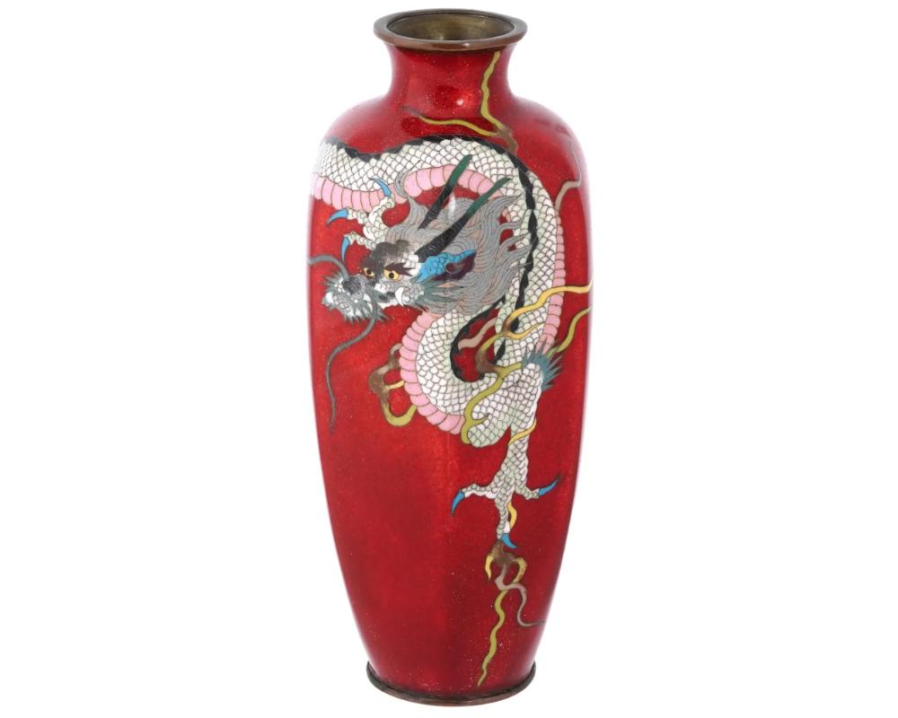 Rare vase japonais en émail sur cuivre. Le vase a un corps en forme d'urne et un étroit col cannelé. La vaisselle est fabriquée dans un design lobé. La vaisselle est émaillée d'une image polychrome d'un dragon sur un fond rouge, selon la technique