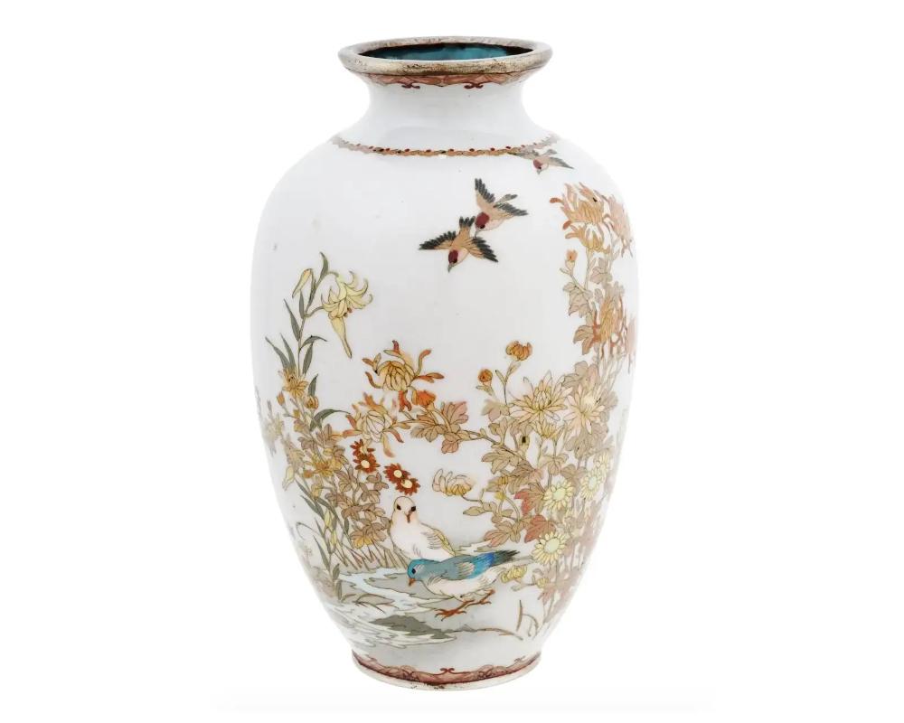 A rare small Japanese, late Ming dynasty, silver wire white enamel vase. The vase has an amphora shaped body and a fluted neck. The ware is enameled with a polychrome image of birds in blossoming flowers made in the Cloisonne technique on a rare