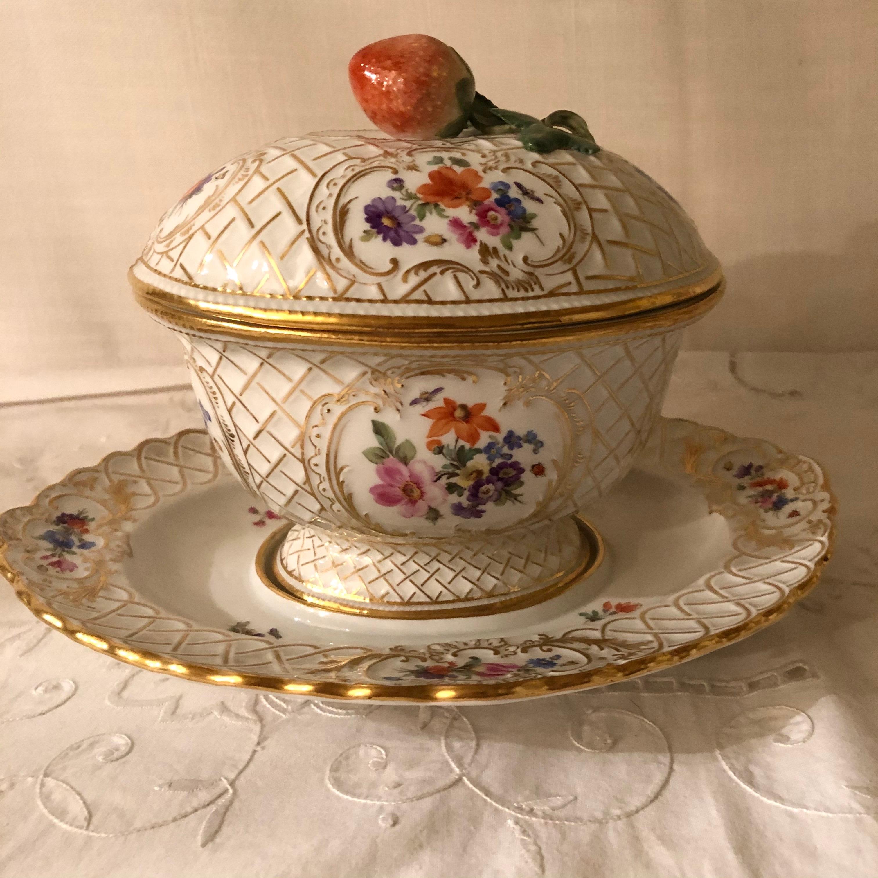 This is a very rare and beautiful Meissen gravy or saucier with a raised strawberry decoration on the cover. The bottom has an attached underplate, and is painted with four cartouches of flower bouquets. The top of the gravy also has four cartouches