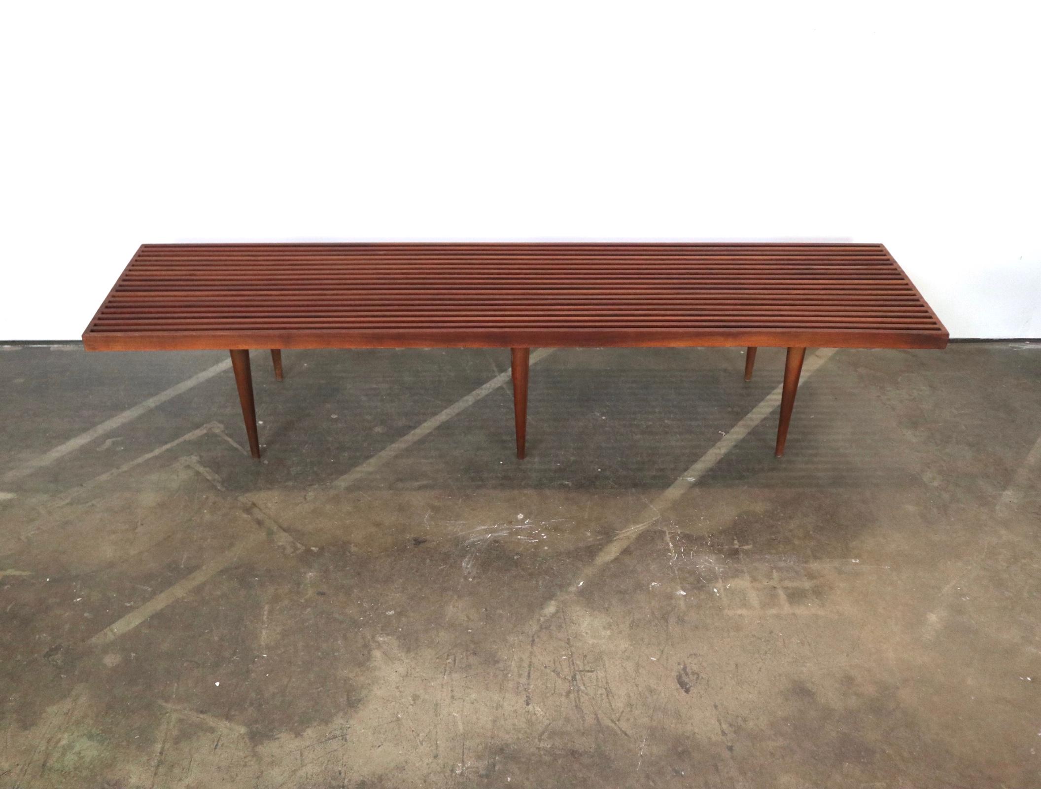 Beautiful Mel Smilow slat bench in walnut. Beautifully executed atop sculpturally tapered legs. In great condition. Legs unscrew for easy shipment or storage. Rager 6 foot length.