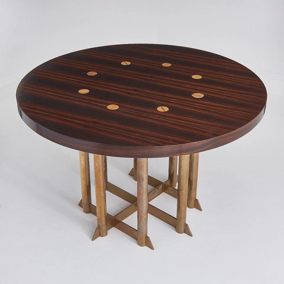 This exquisite mid-20th century dining table is a rare example of masterful Brazilian modernist design, crafted from rich Jacaranda wood. 

Featuring a striking round tabletop with inlaid circular brass details, the piece showcases the natural