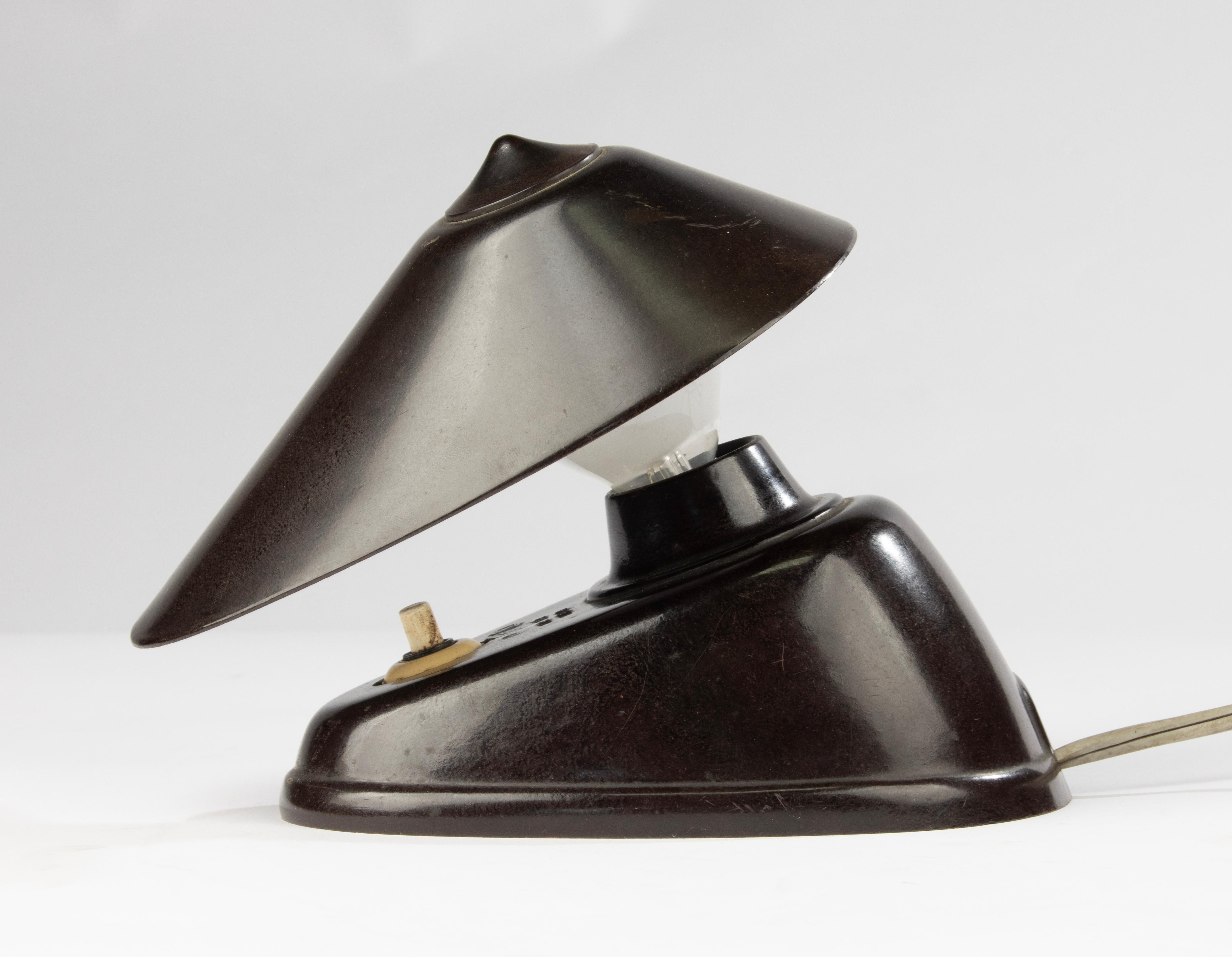 This sculptural and compact desk lamp, attributed to Hala Zeist (Netherlands), is a striking example of early mid-century industrial design. Produced around the 1950s, the lamp is made entirely from dark brown Bakelite — a prized early plastic known