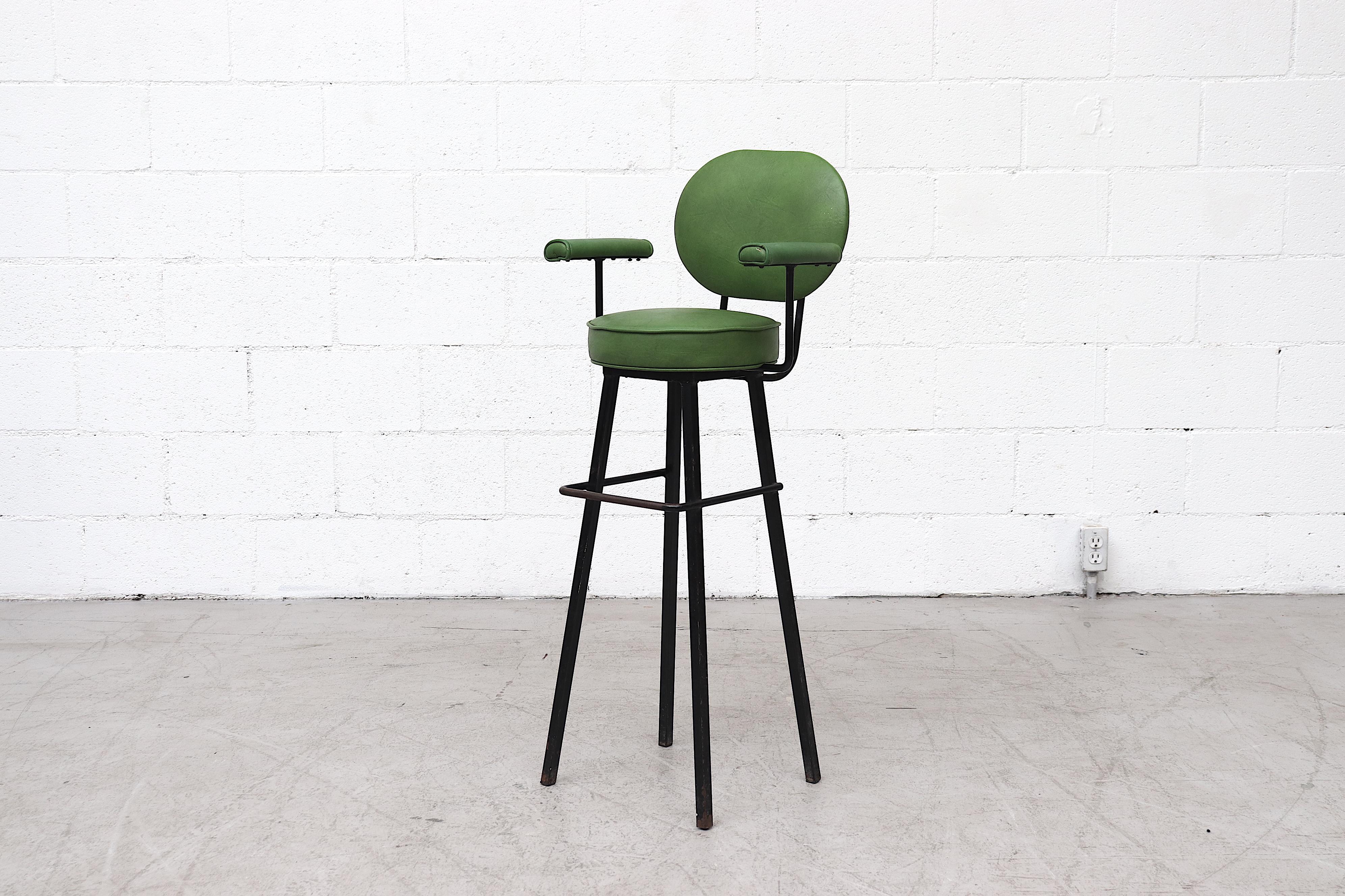 Midcentury child's high chair with emerald green Skai upholstery and black enameled tubular frame. In original condition with upholstered arm rests and 20” high foot rest. Visible signs of wear including scratching and mild enamel loss.