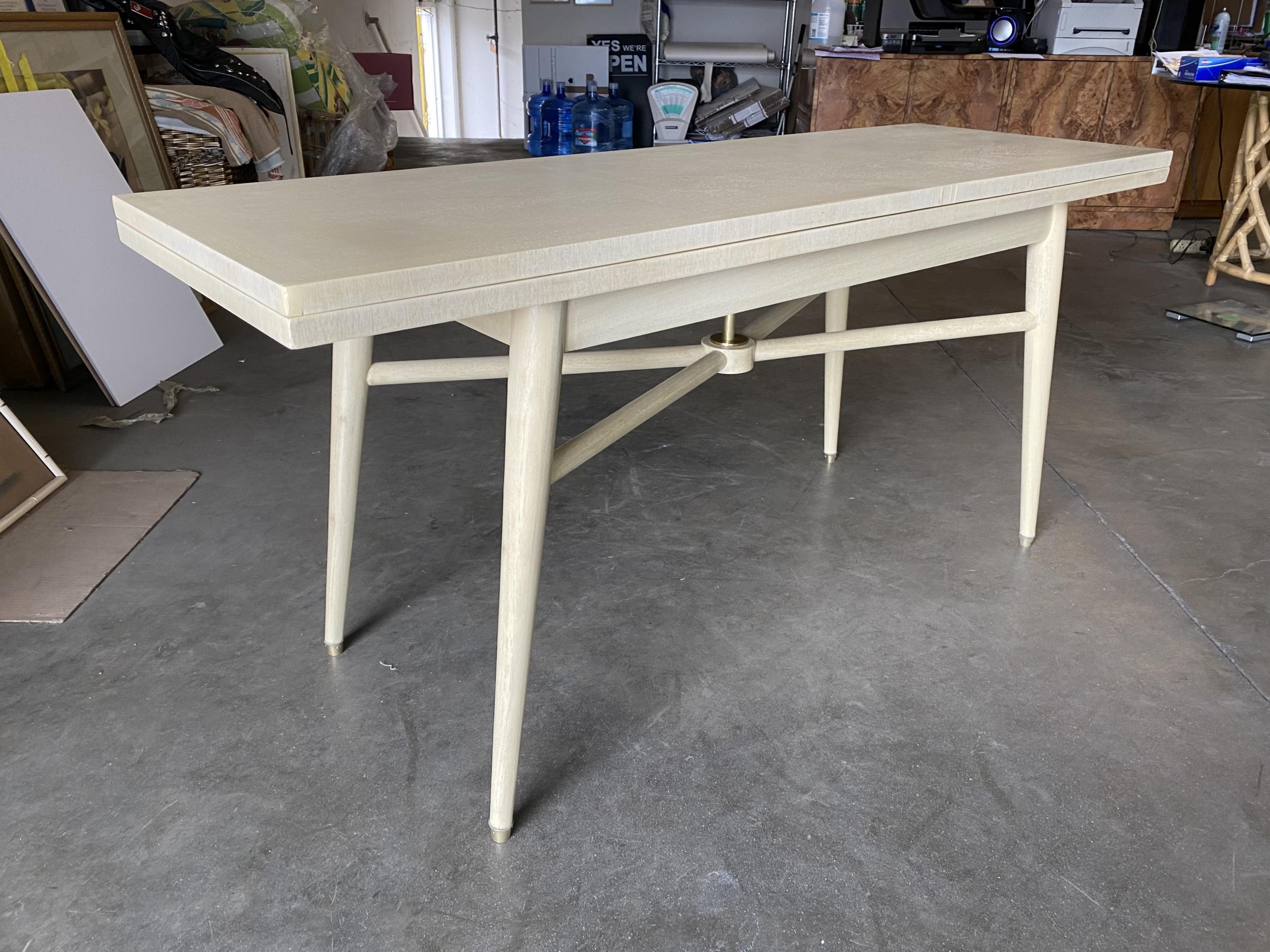 Rare Mid-Century Modern flip top long convertible console table which flips open to 6 person dining table. The table features tapered legs with brass accents and X design between the legs. 

The table is 20