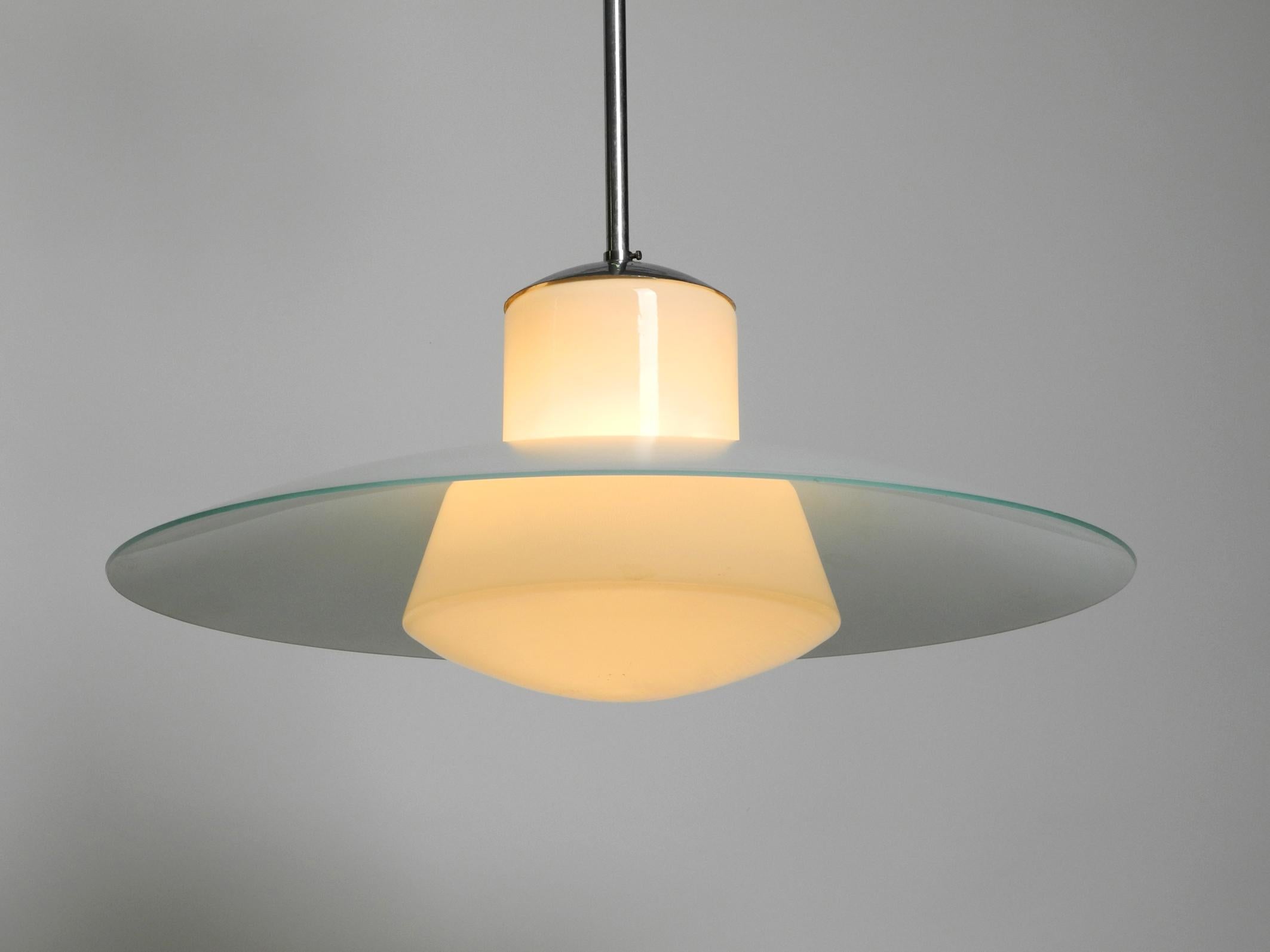 Wonderful original Mid Century Modernist XL glass pendant lamp by Wilhelm Braun Feldweg for Doria. Very rare in this huge double glass version.
Elegant minimalist design with an opaline glass shade and a huge, 
slightly blue glass reflector for
