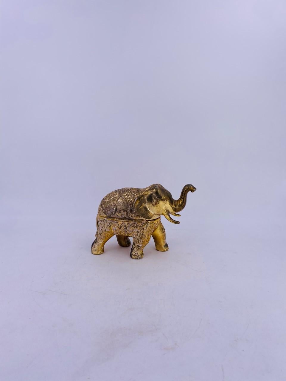 Beautifully gilded metal with patina music box in the shape of an elephant. This unique music box is vintage and made in Japan. The figure opens up and presents a beautiful red interior with a wind up handle that allows the mechanism to produce an