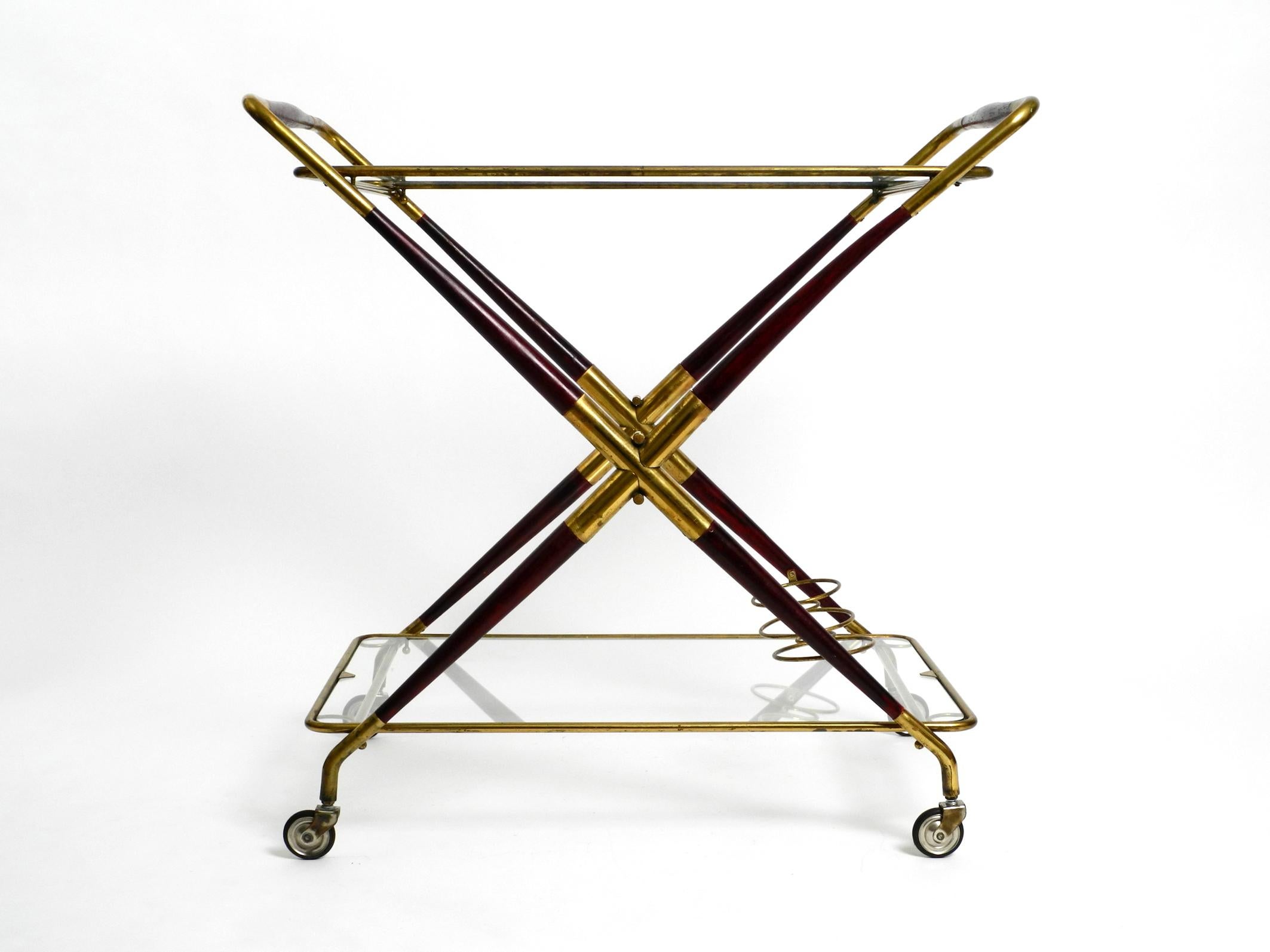 Rare midcentury Italian folding serving and bar cart.
Designed by Cesare Lacca. Made in Italy.
Great fancy 1960s Italian design.
Both glass shelves can be removed and the frame can be folded up.
Frame is made of brass and mahogany wood. Both