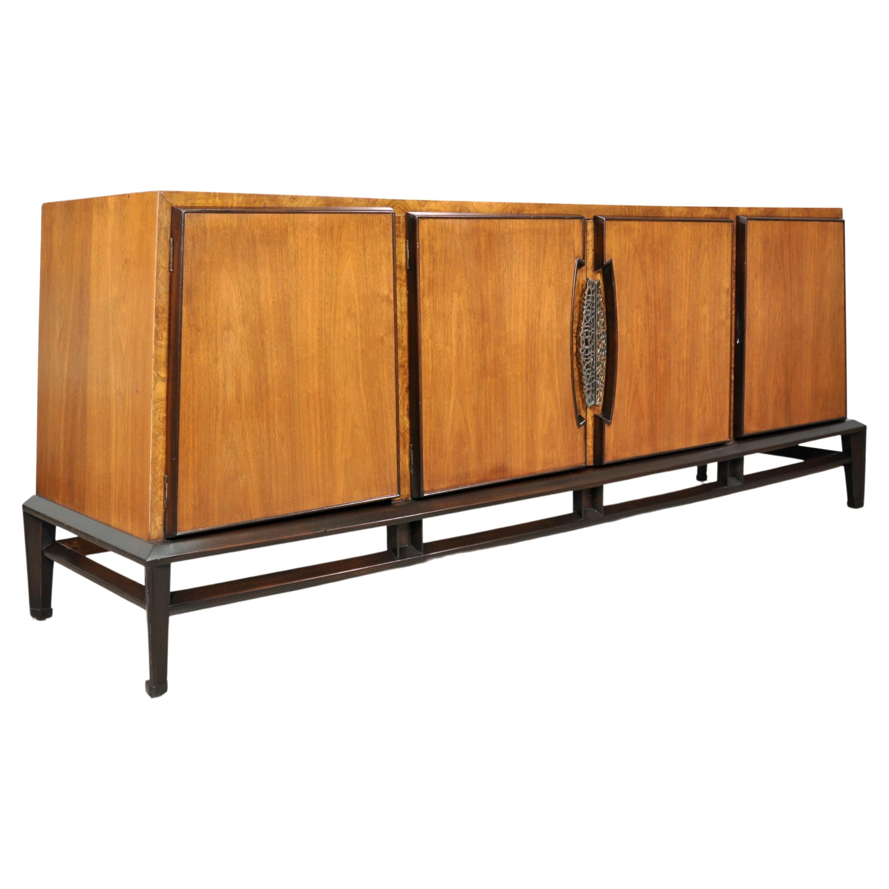 A stunning vintage triple dresser designed by wife and husband team Helen and Hobey Baker for Baker Furniture. The Mid-Century Modern cabinet features a two-toned, Asian inspired, sleek walnut frame with burl accents and brass hardware. With a total
