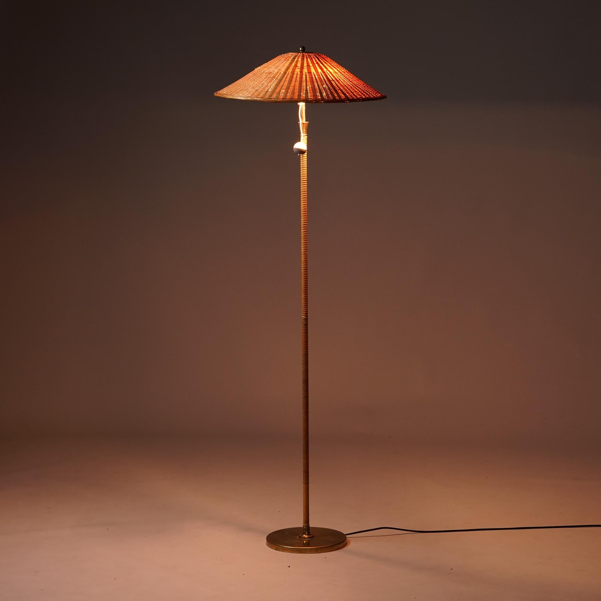Rare mid-century modern floor lamp manufactured by Itsu in the 1950s. Brass details, rattan shade, rattan-covered stem. Good original condition, beautiful patina on the brass details. Rattan shade has been changed later. The shade is vintage.