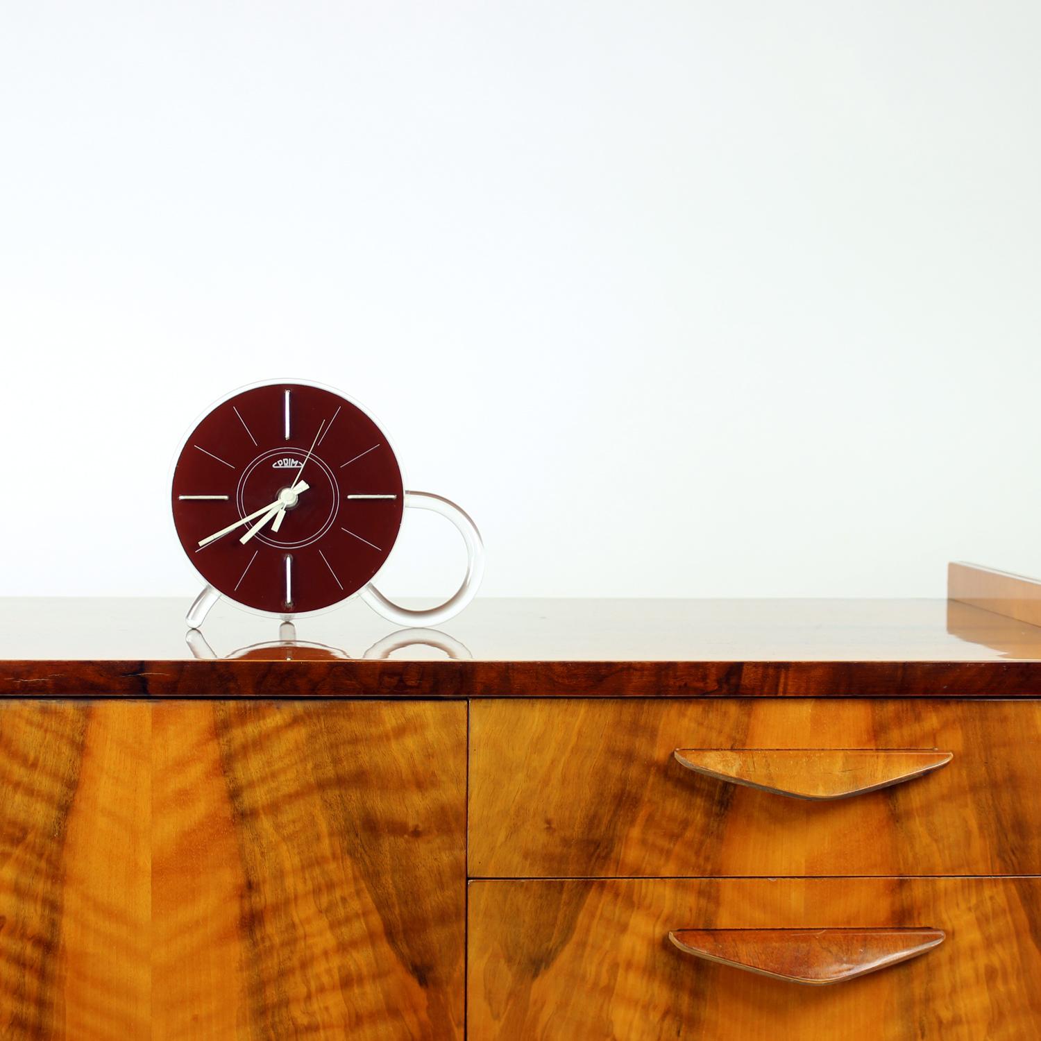 A beautiful and rare freestanding table clock, produced in Czechoslovakia by the renowned Prim company during the 1960s. This exceptional example of Mid-Century Modern design features a sculptural plexiglass body with elegantly molded legs — a