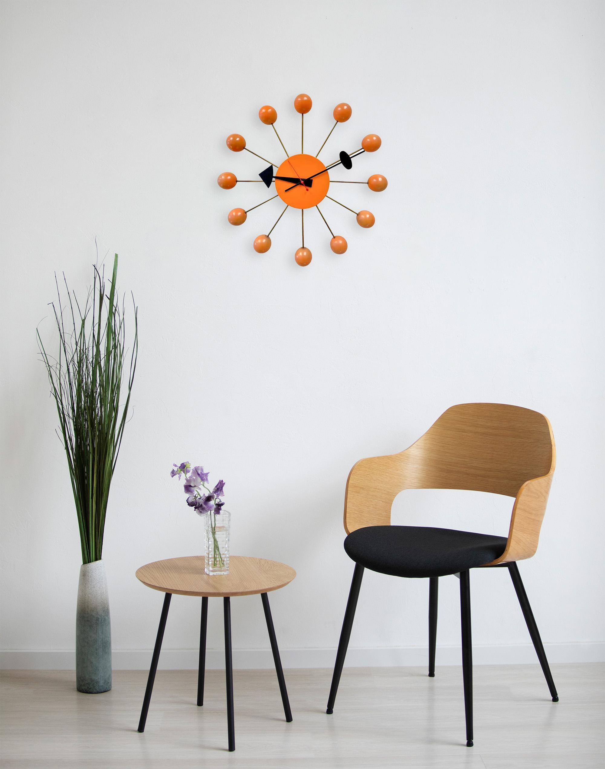 An original George Nelson ( 1908- 1986)  Mid Century Modern Ball Clock model 4755.  This iconic clock features a distinctive and modern design with a mid-century aesthetic. The central face is a solid orange circle from which twelve metal rods