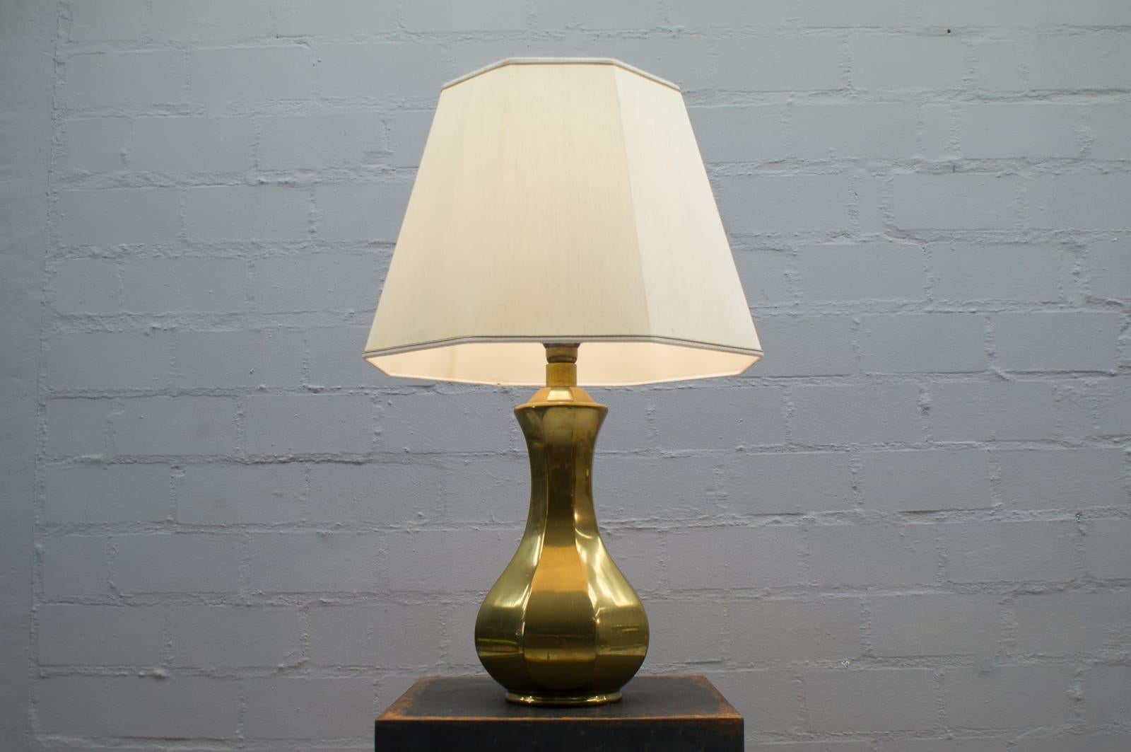 Elegant, solid brass table lamp from the 1960s. Beautiful patina and lighter traces of use.

Formed from one piece.

The total height is 77cm, the lamp foot measures 48cm. The total diameter is 50cm, the lamp foot measures 20cm. 

The lamp