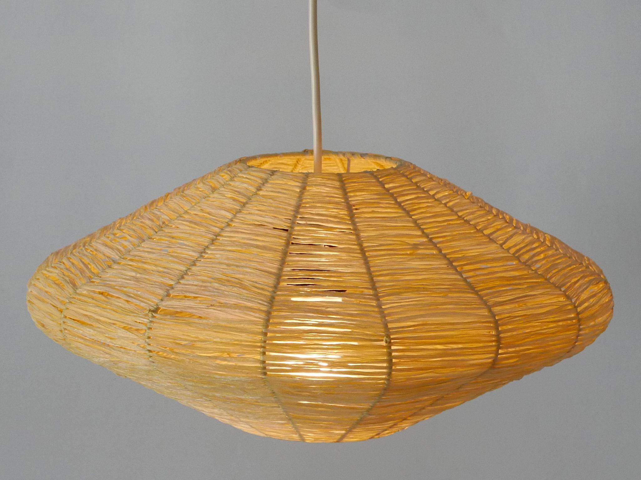 Rare, elegant and highly decorative Mid-Century Modern pendant lamp / hanging light. Manufactured in Germany, 1970s.

Two identical pieces available!

Executed in raffia bast and metal, the pendant lamp comes with 1 x E27 / E26 Edison screw fit bulb