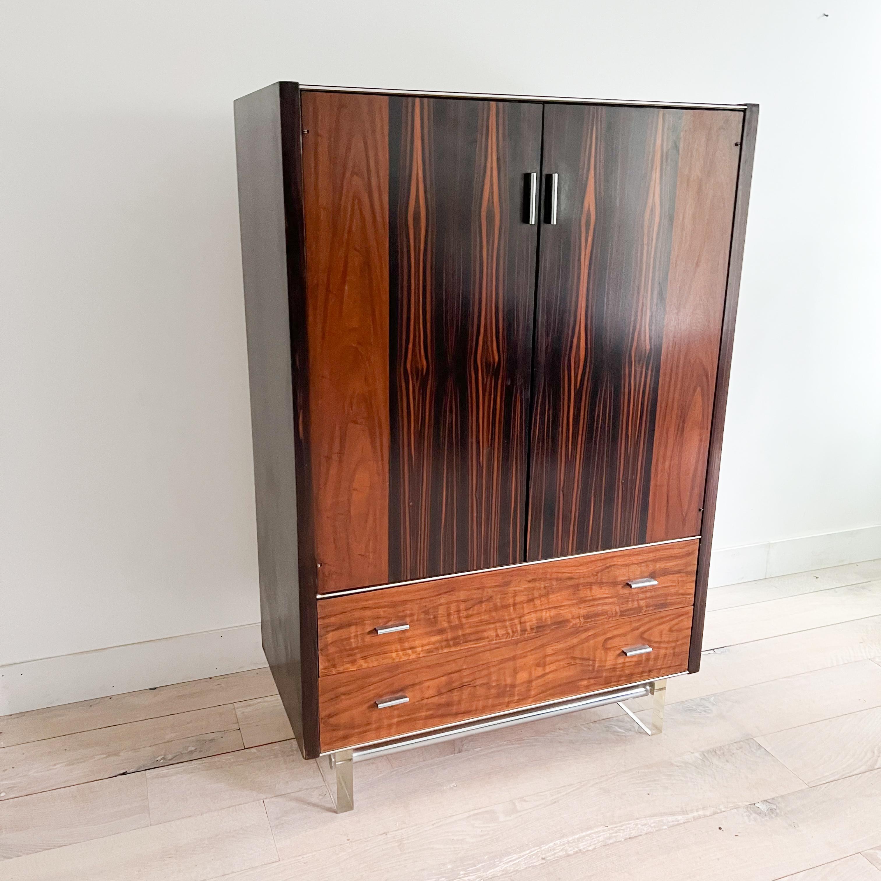 Add a touch of timeless elegance to your space with this hard-to-find piece from the Mid-Century Modern era. Crafted from luxurious rosewood and featuring a sleek lucite base, this gentlemen's chest by Modernage exudes