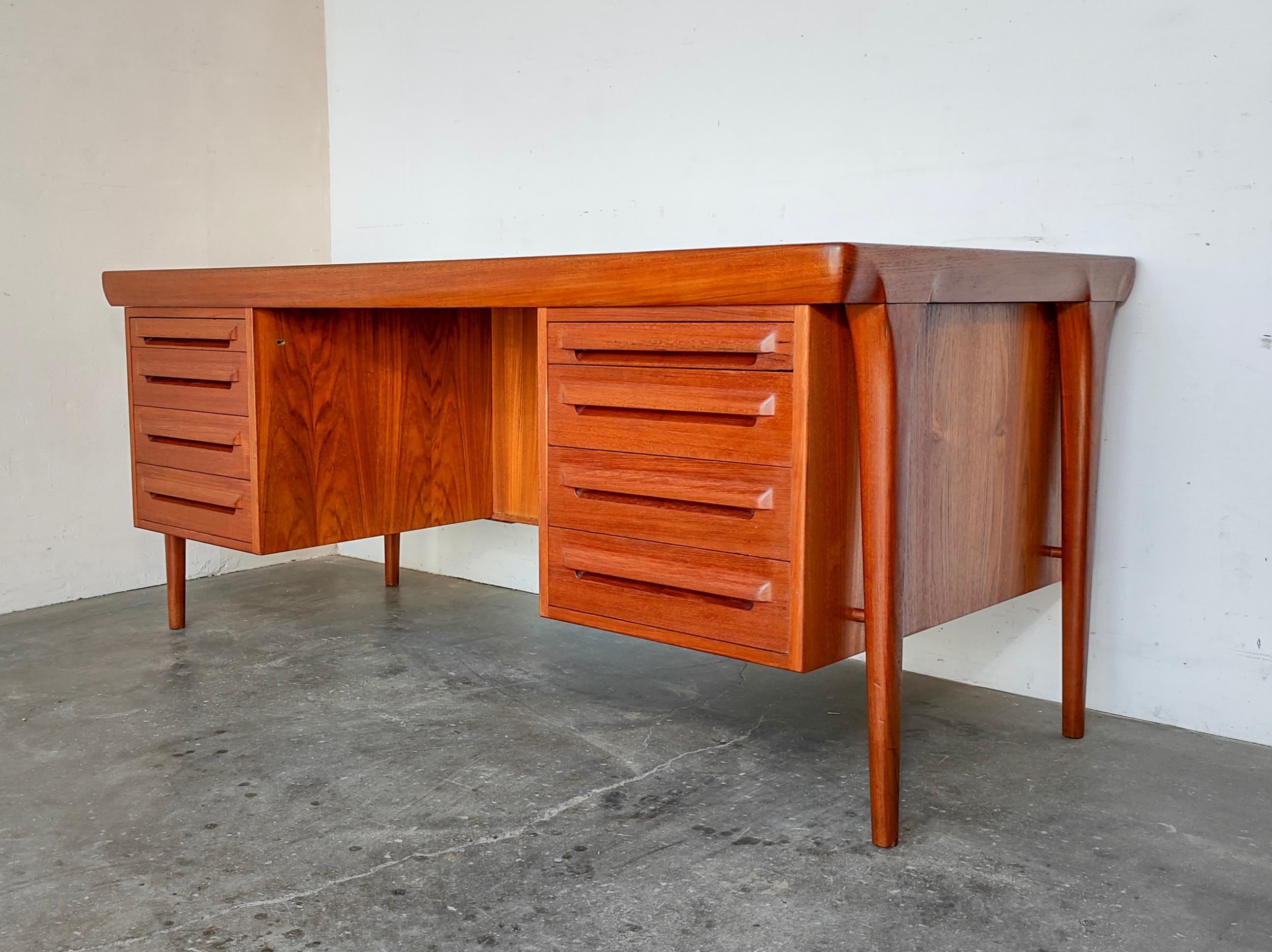Stunning rare teak executive desk with sculpted legs and drawer faces designed by Ib Kofod Larsen and made in Denmark by Faarup Mobelfabrik. It has six drawers and two pull-out trays disguised as a top drawer on each side. The tray on the left has