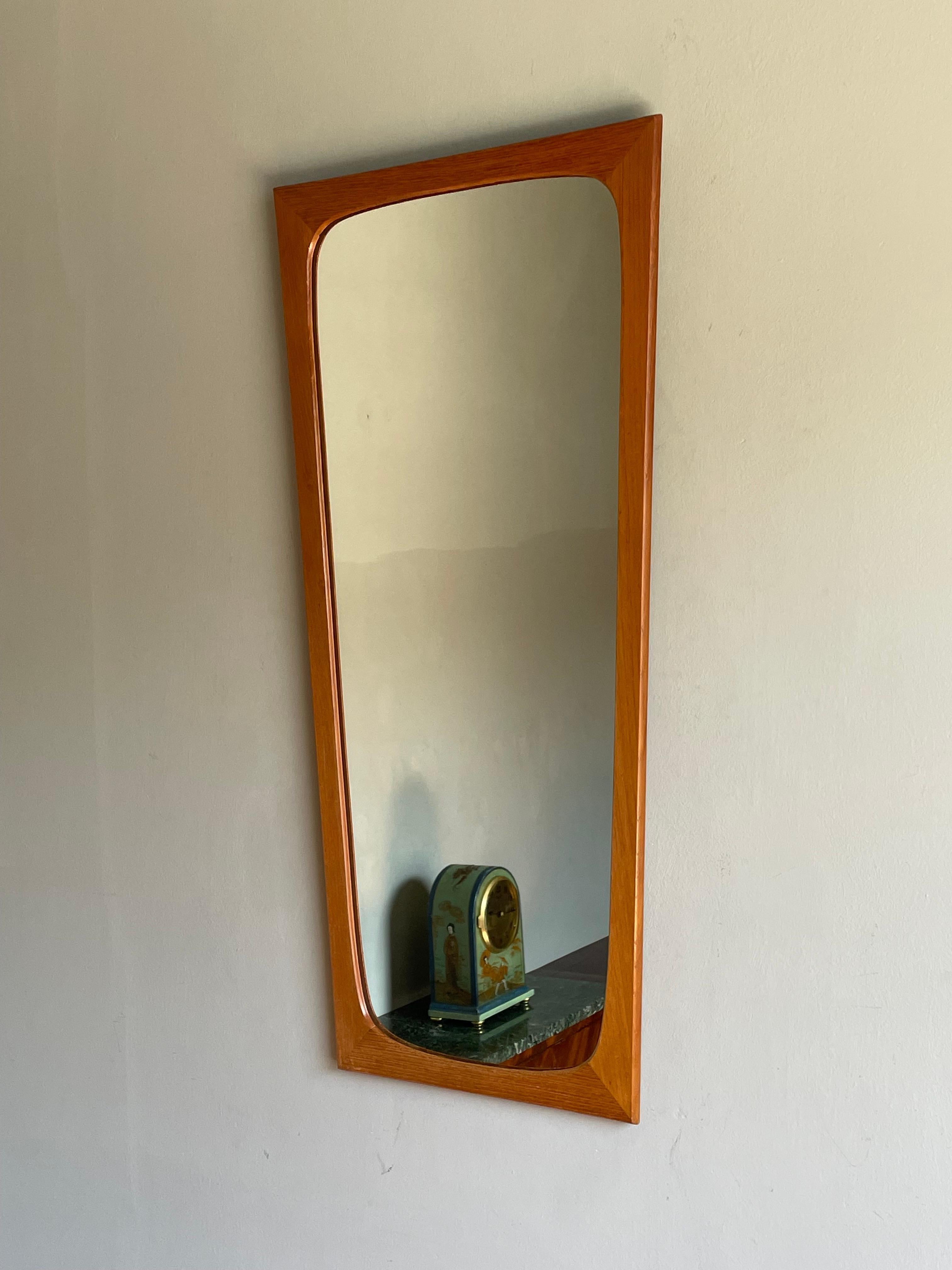 Sleek, stylish and clean midcentury mirror for wall mounting.

This midcentury, teakwood wall mirror is in superb condition from top to bottom and we think it is an interior designer's dream. Its design and light (or should we say fresh) color makes