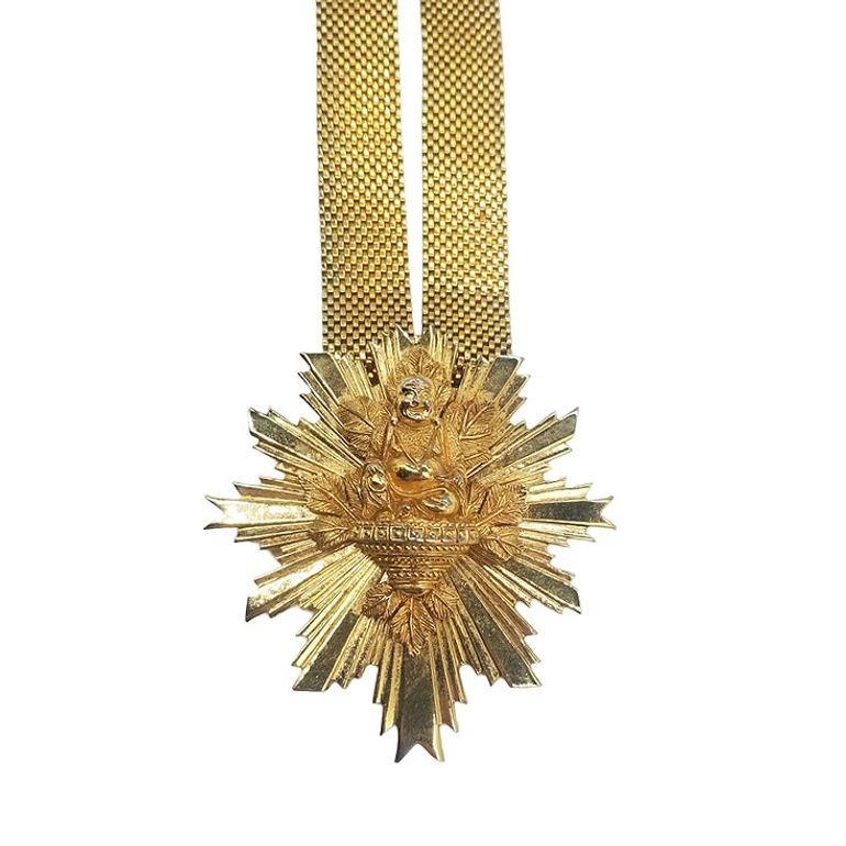 Elevate your style with the timeless elegance of this Vintage Nettie Rosenstein Gold Plated pendant necklace, featuring a Buddha accent and a secure hook clasp and substantial mesh chain gracefully adorns the neckline, while the substantial 3