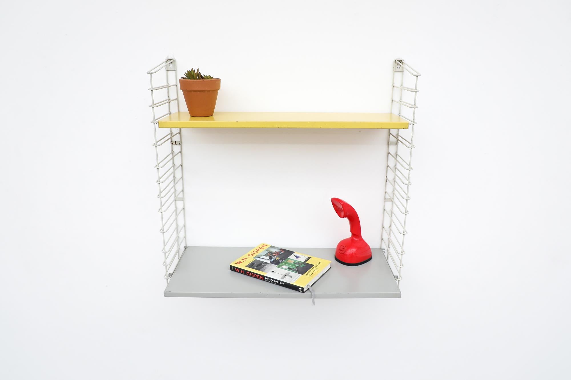 Midcentury TOMADO industrial shelving with a yellow shelf and grey extended desk shelf on white enameled metal wire risers. Designed by Jan van der Togt. Shelves rest on the wire risers and can be arranged to different heights. In original condition