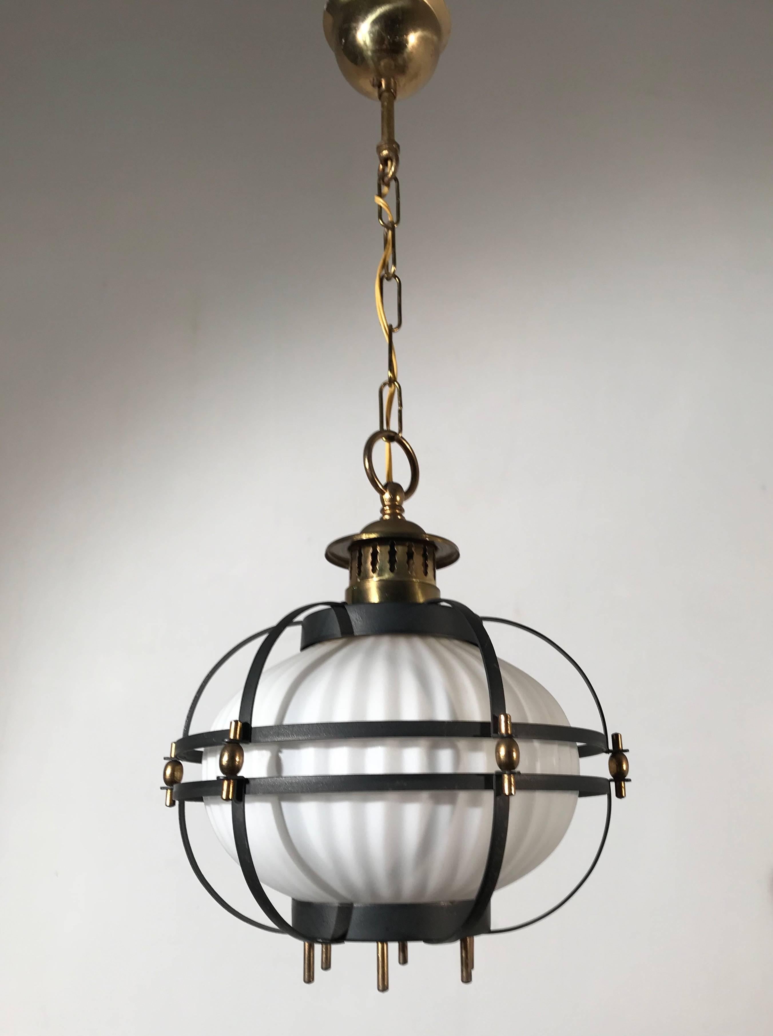 Stylized maritime pendant with a modern twist.

The basic design underneath this Mid-Century Modern light fixture is that of a ships lantern. The cage would protect both the sailors and the glass shade inside. The earliest ships lanterns were much