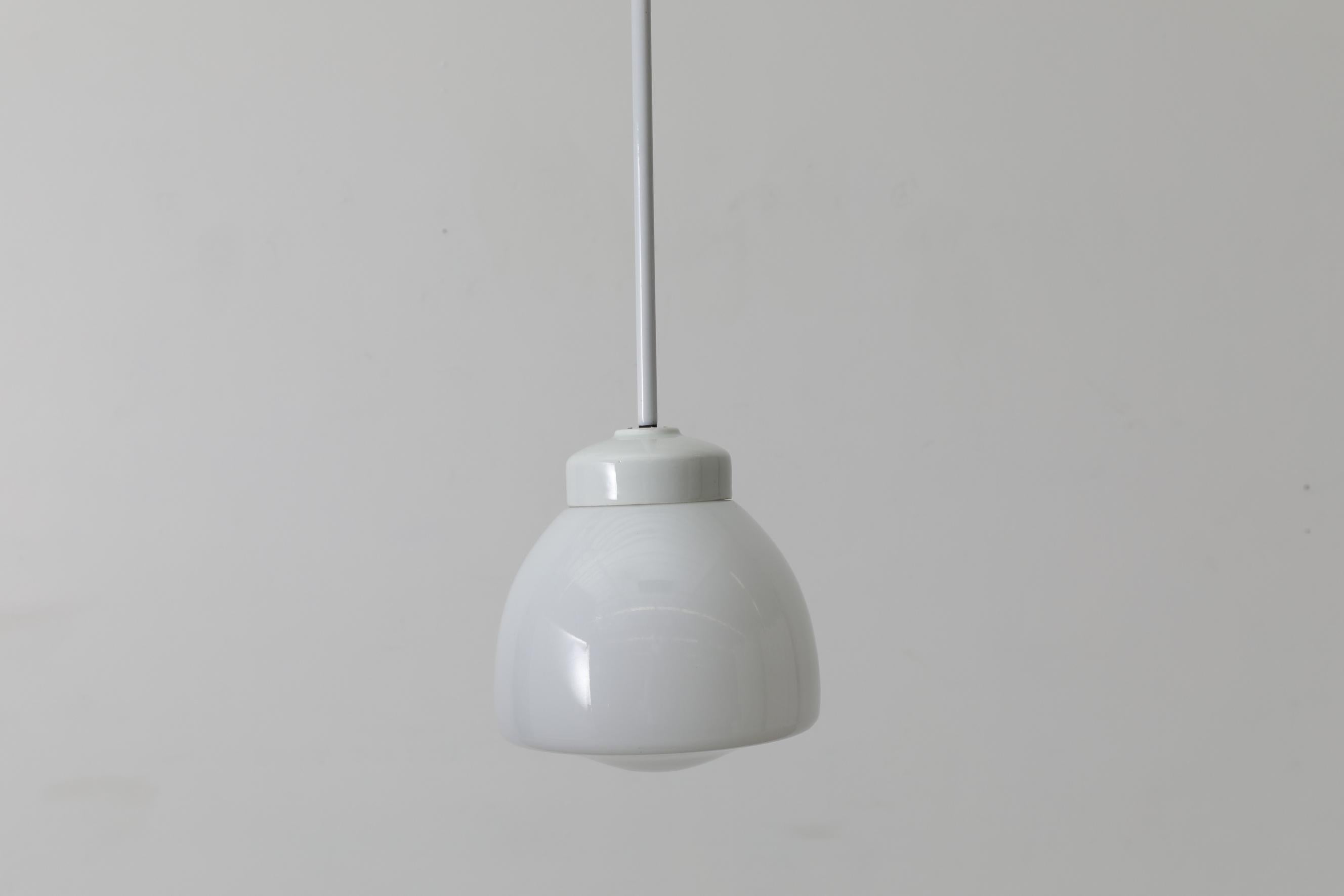Wagenfeld pendant with vintage opaline glass shade and ceramic mount with white enameled metal stem. In good original condition with light signs of wear, consistent with its age and use. There is no canopy.