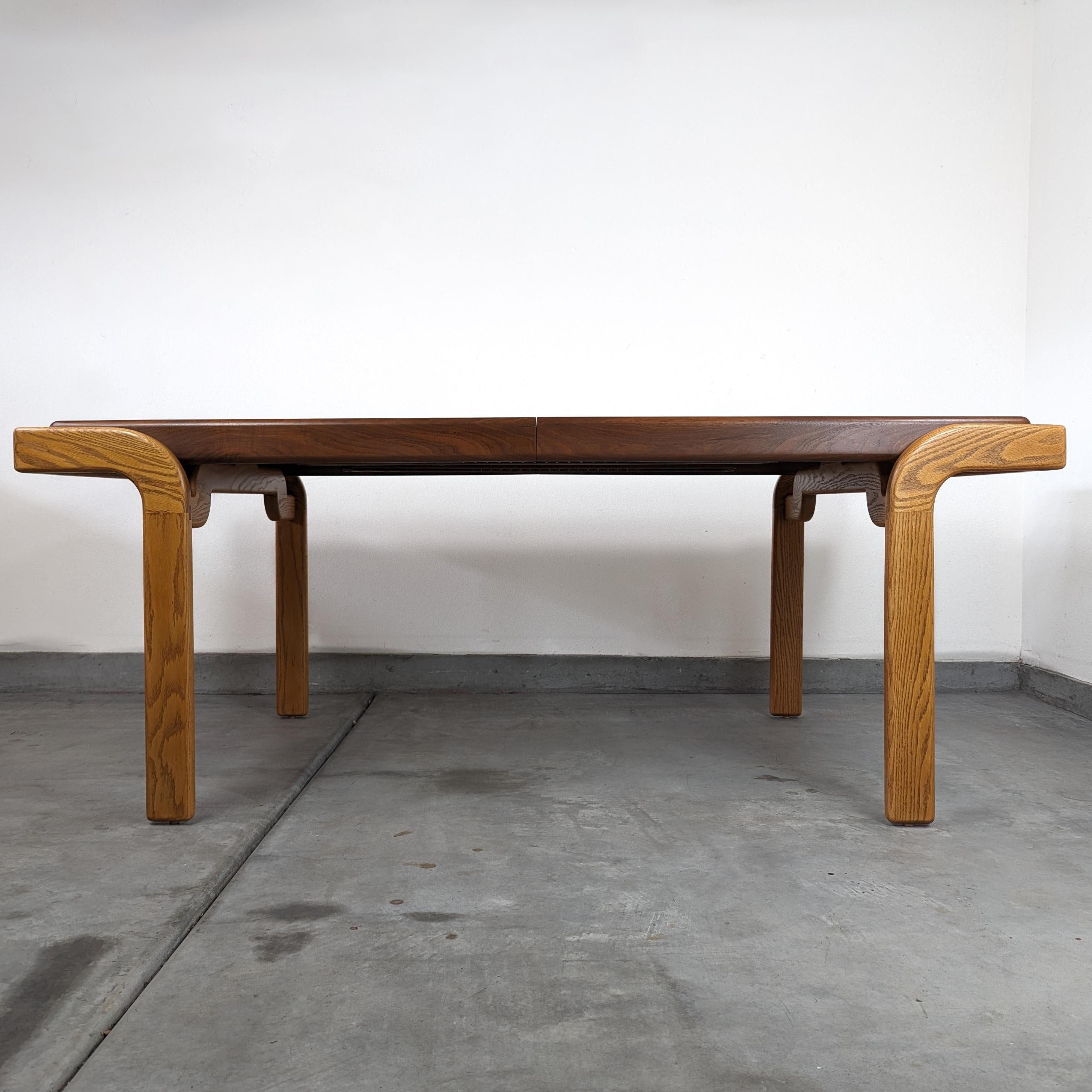 Elevate your dining room with this exquisite vintage dining table, a testament to the unparalleled craftsmanship and innovative design ethos of the 1970s. Believed to be a custom piece from the studio of renowned designer Lou Hodges, this table