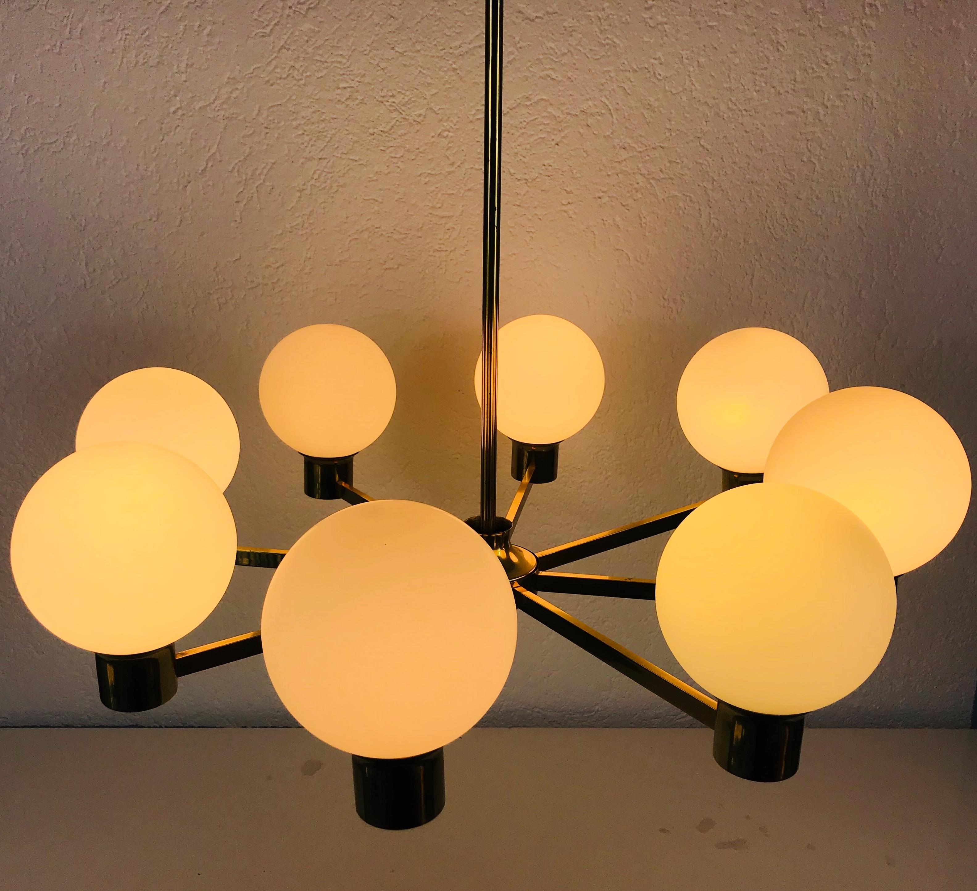 Mid-Century Modern chandelier made in the 1960s. It has eight metal arms, each with an opaline glass shade in extraordinary shape. 

The light requires eight E14 light bulbs.