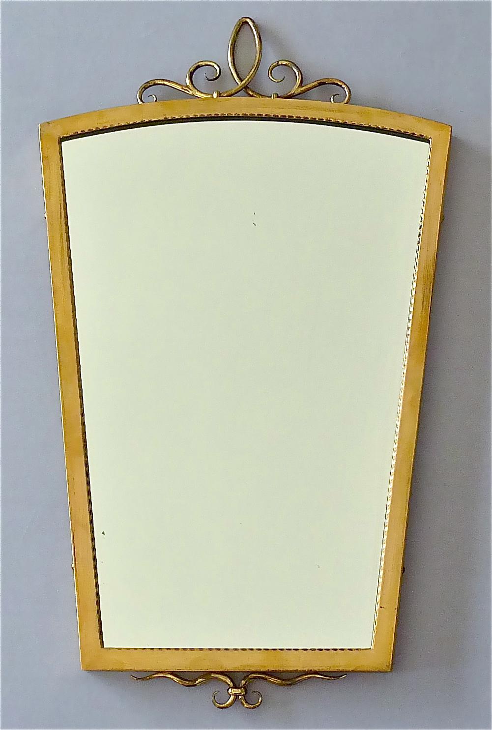Rare Midcentury Gio Ponti style Italian wall mirror, Italy 1950s. The gorgeous vintage mirror is made of gilt brass and original mirror glass and has a beautiful upper and lower brass decoration very in the style of Gio Ponti. The old mirror stays
