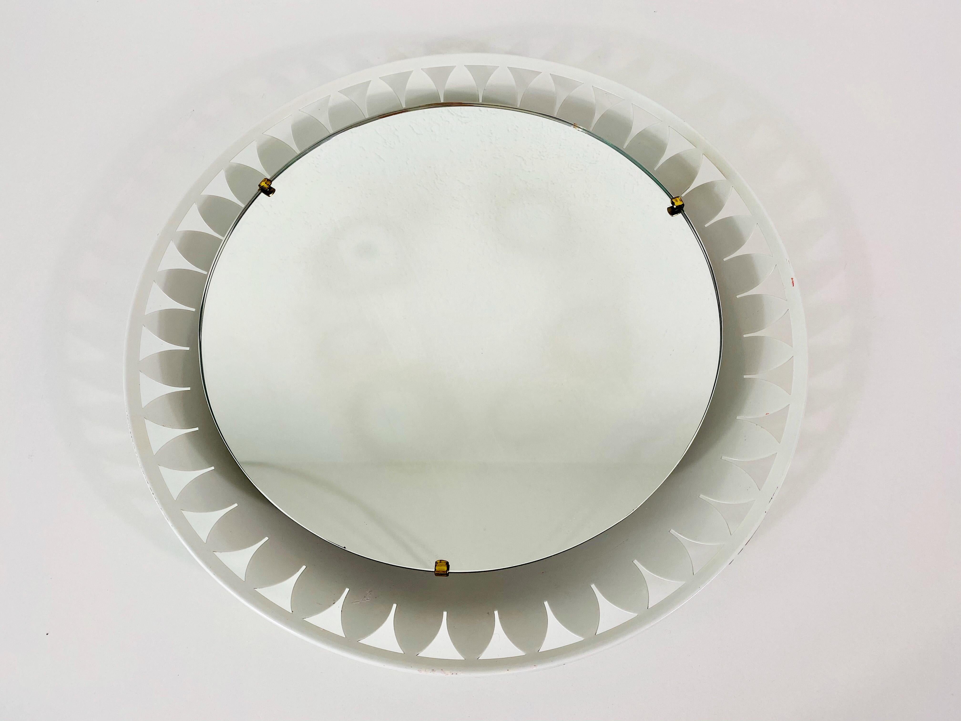 Uno specchio da parete illuminato Hillebrand degli anni '50 prodotto in Germania. Lo specchio ha un design rotondo in metallo. All'interno della cornice sono presenti lampadine E14. 3 viti in ottone fissano il vetro alla cornice in alluminio. Lo