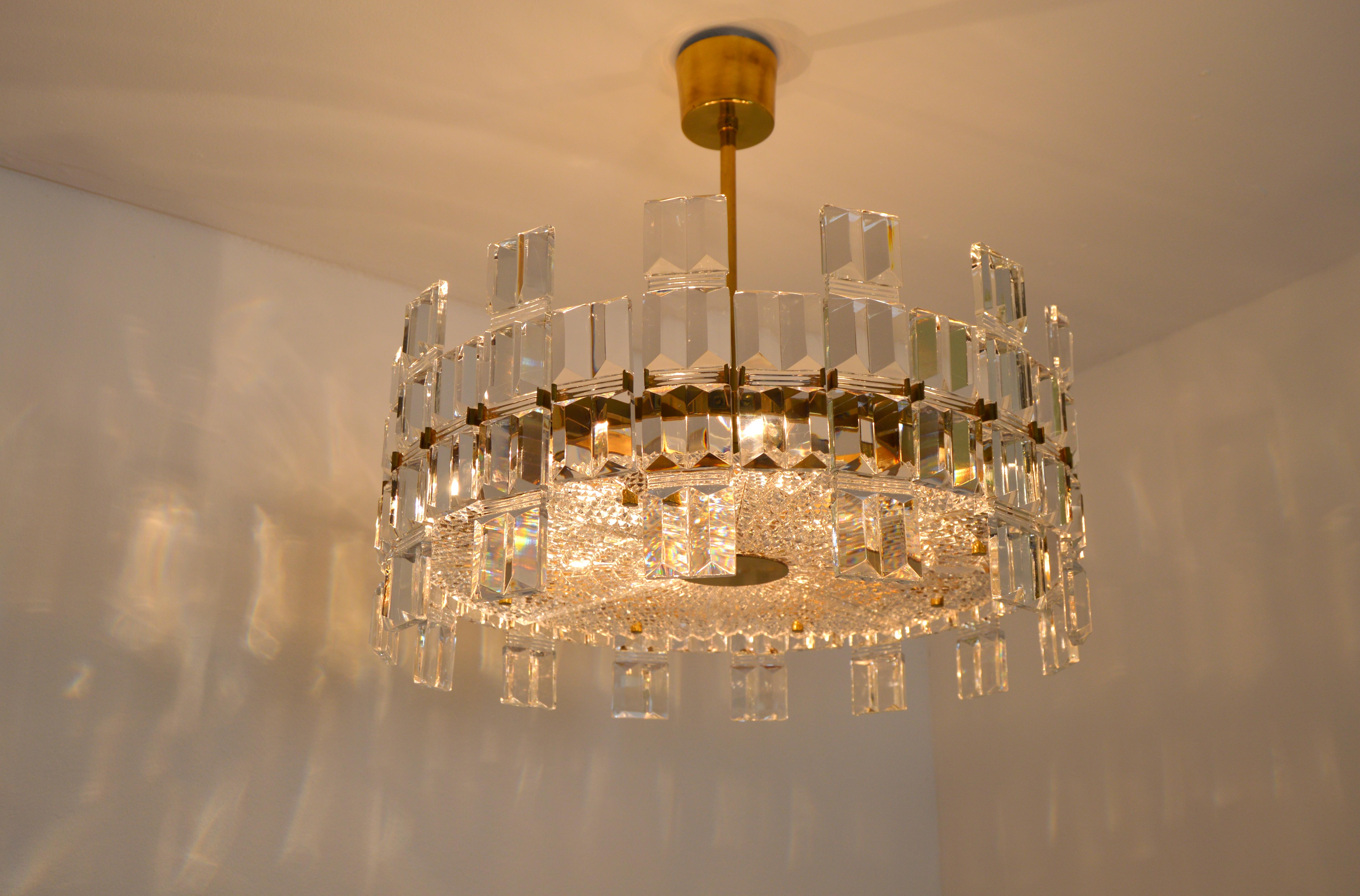 A rarley seen luxurious chandelier designed by Carl Fagerlund for Orrefors, Sweden.
Crystal glass and brass. It consists of 14 large and 14 smaller glass units that surround a round metal frame. Each glass unit is clamped between four brackets. A