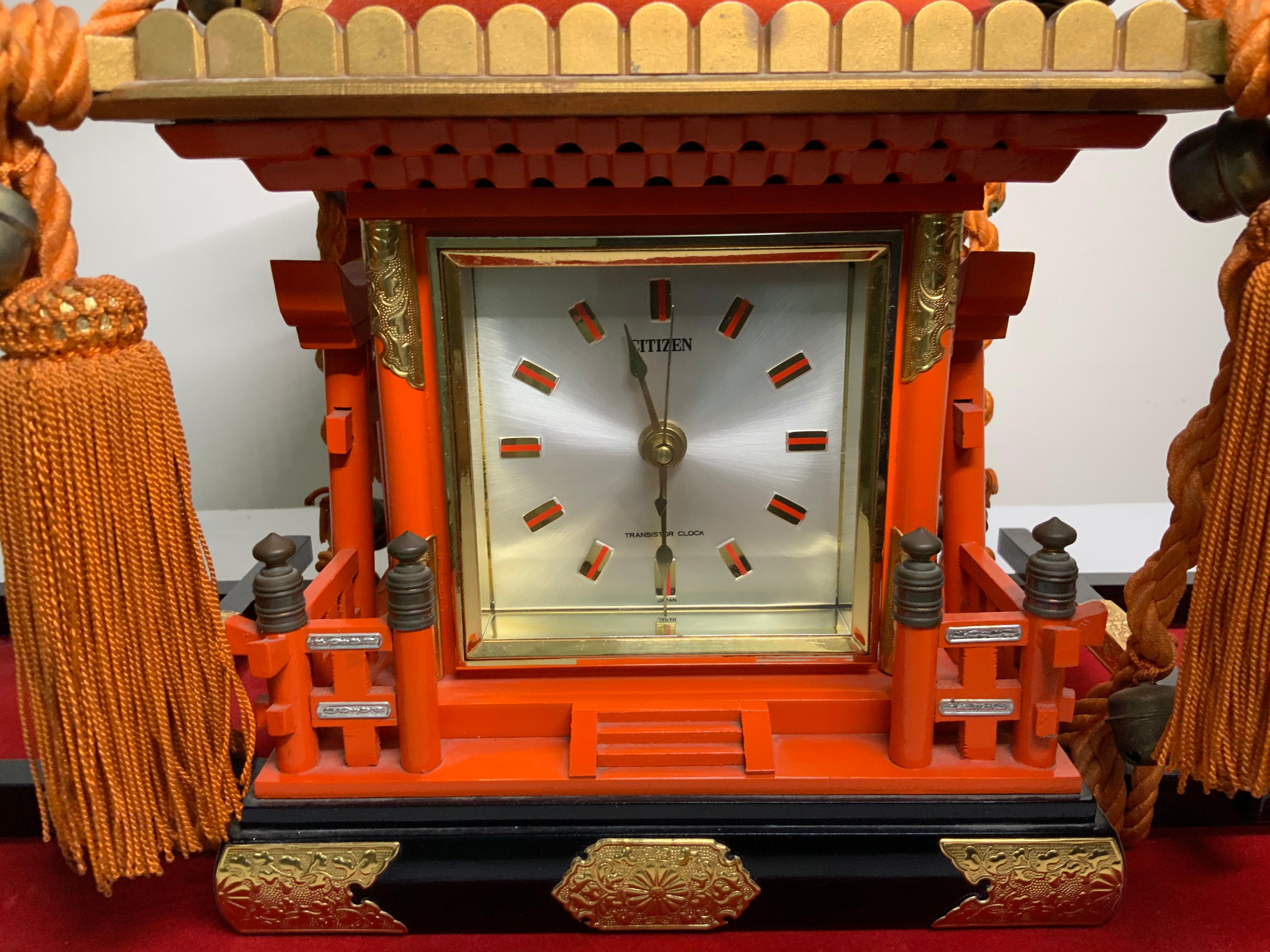 This is a square Citizen clock mounted in a shaped Mikoshi Palanquin-Shinto Shrine wood (This is a vehicle that the Japanese people used to transport a deity during festivals). The Mikoshi is hand painted orange with gold details. There is a large