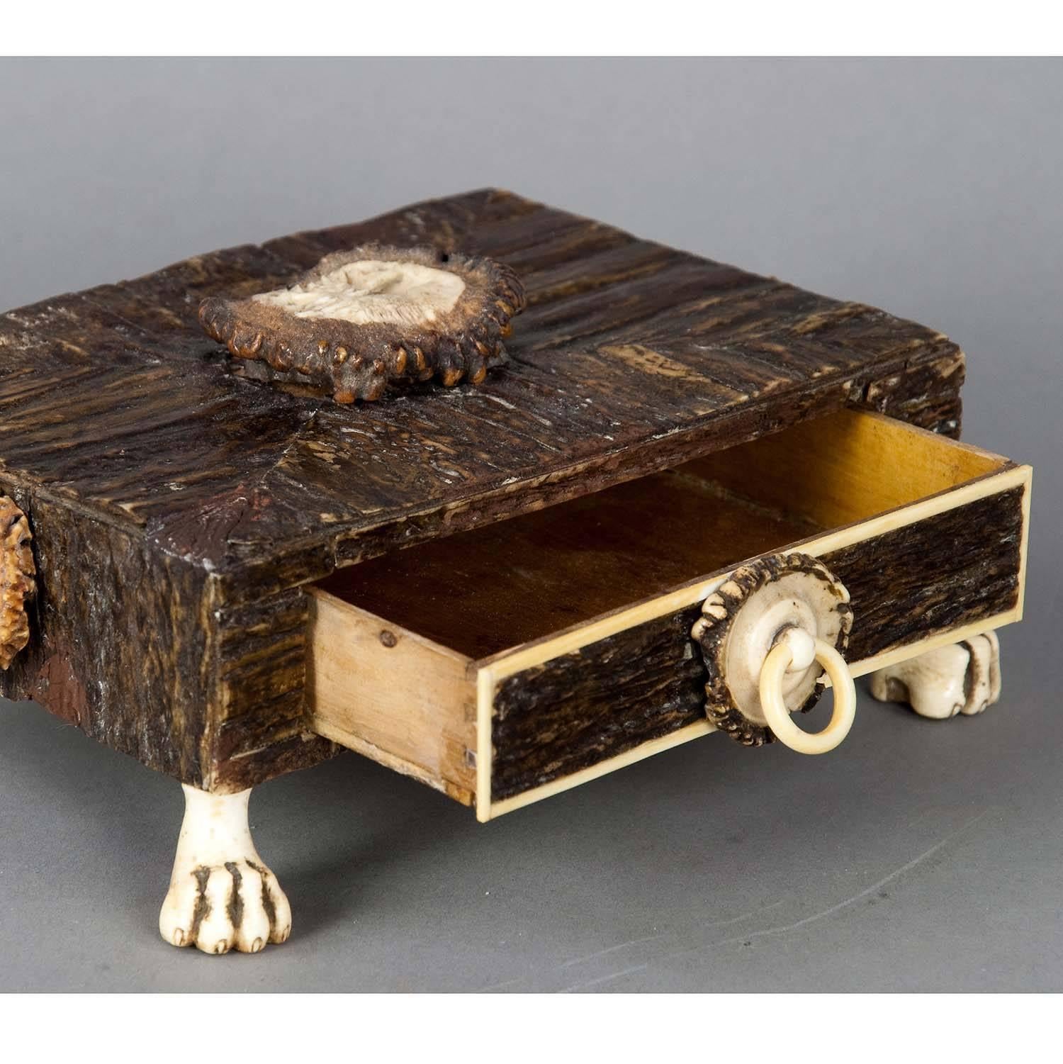 A marvelous drawer casket. Made of wood, veneered with horn pieces. Sides decorated with horn roses, on top a carved horn rose. Feet made of horn, carved in the shape of lions paws. Executed circa 1860. (veneer partly restored)

Measure: width