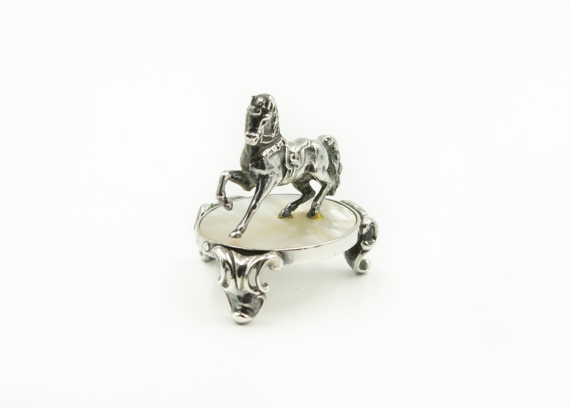 Originally Watrous made bells and iron nickel-plated toys, this is a rare example of one of his horses done in sterling silver. The horse is fitted with a saddle and bridle and looks like he or she is pracing on a sliver of mother of pearl stand