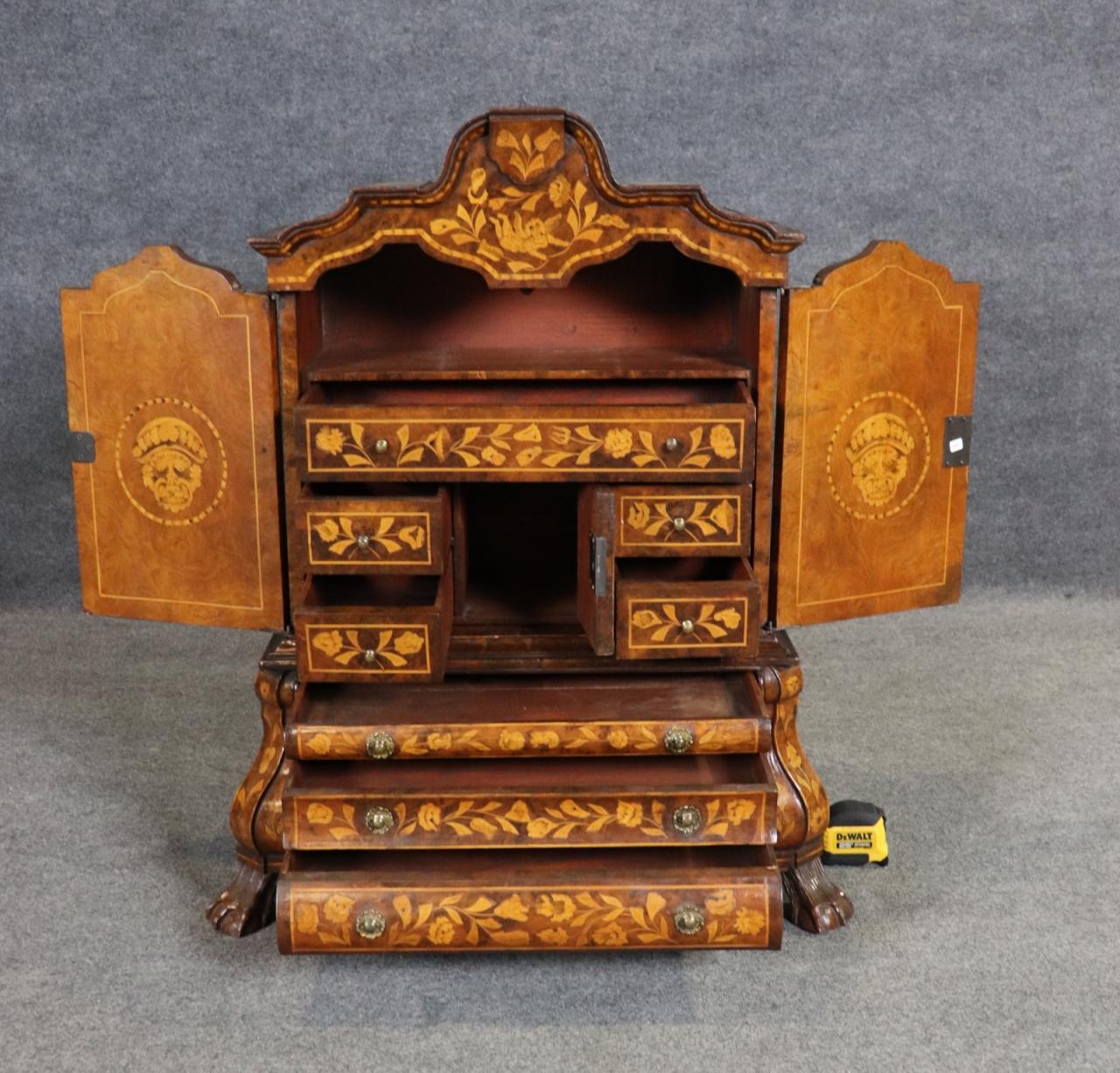 Nous vous présentons une superbe armoire miniature en marqueterie hollandaise, un exemple magnifiquement travaillé des arts décoratifs européens traditionnels. D'une hauteur de 37 pouces, d'une largeur de 31 pouces 1/2 et d'une profondeur de 14