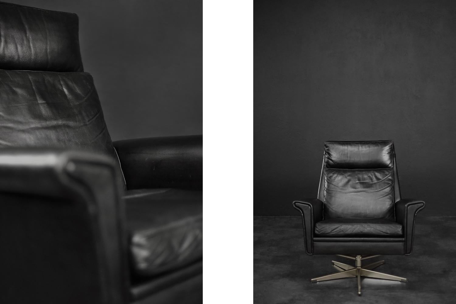 This rare office armchair was designed by the Danish designer Georg Thams during the 1960s. It is upholstered in black natural leather. It has three loosely placed pillows. The armchair is spacious and comfortable, and the wide armrests additionally