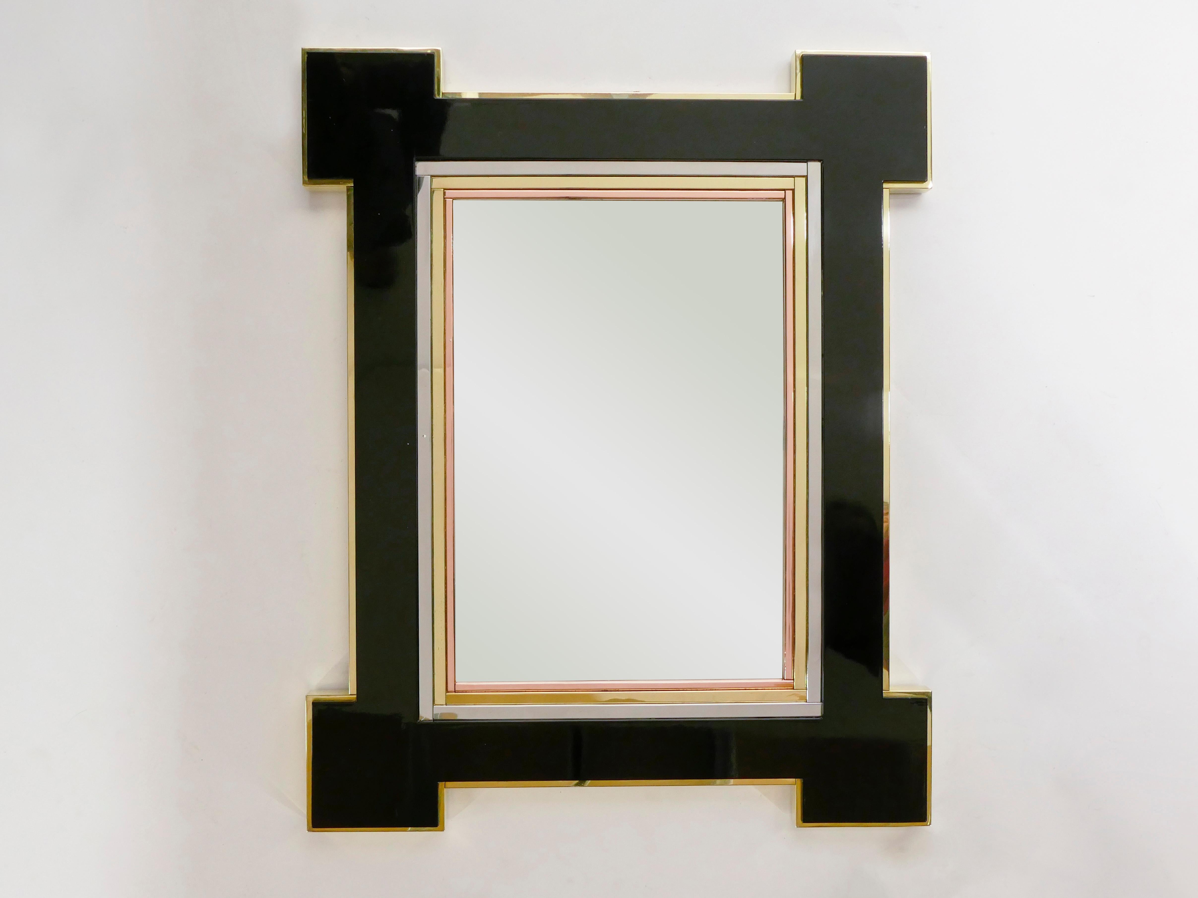 The black lacquer and mix of metals with brass copper and chrome layers make up the decorative frame of this beautiful and rare large wall mirror designed by Alain Delon and edited by Maison Jansen in 1975. It was first presented in Salone del