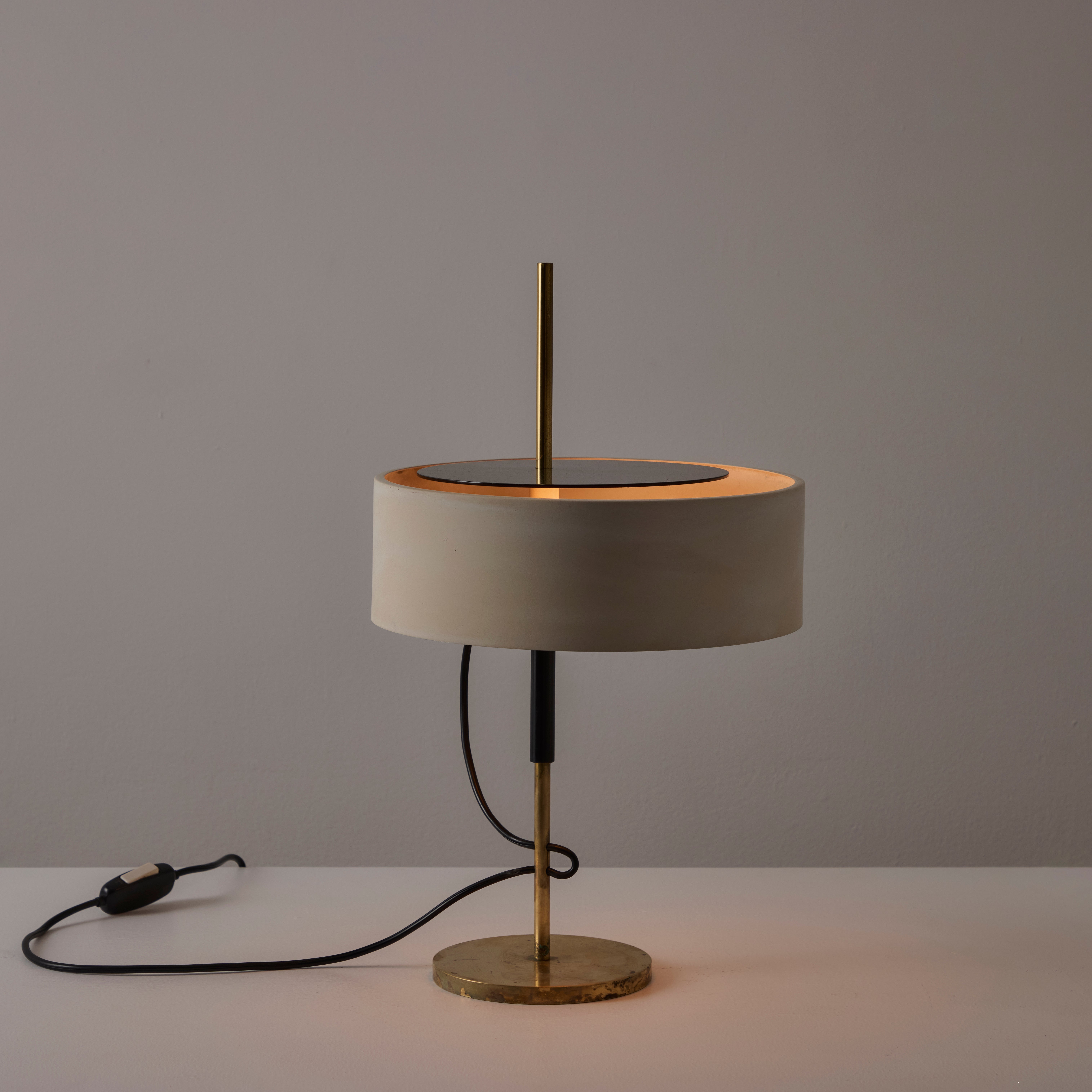 Model A 243 Table Lamp by Angelo Ostuni and Renato Forti for Oluce. Designed and manufactured in Italy, in 1953. Bone colored aluminum drum shade, black enameled steel upper diffuser and brass detailing. The light holds a dual e14 socket-type,