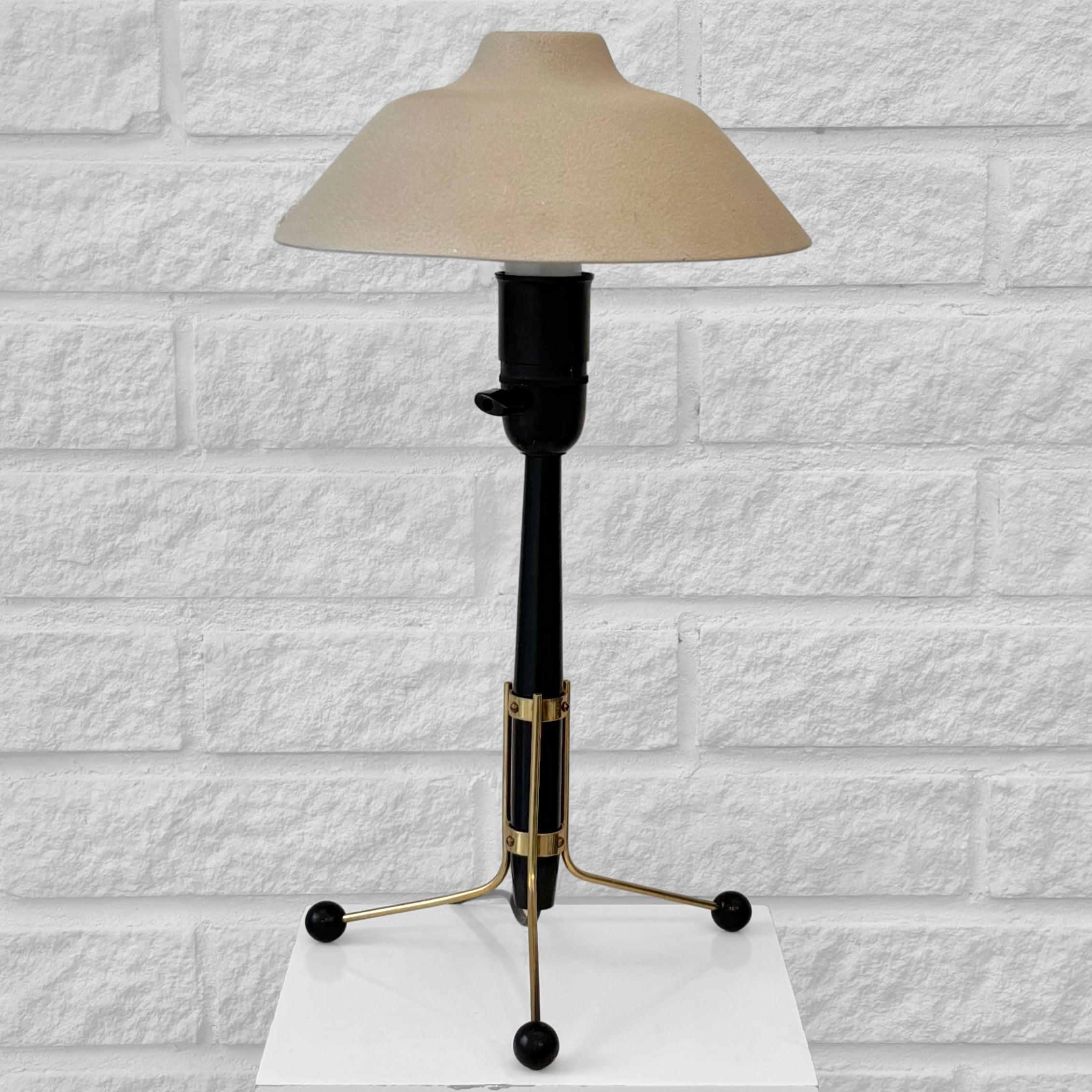 A modernist Scandinavian 1950s table lamp, model E1278, produced by the renowned Swedish lighting manufacturer ASEA Belysning. It features a tripod brass base supporting a wooden cylinder, resting on three sphere-shaped feet. The lamp is complete