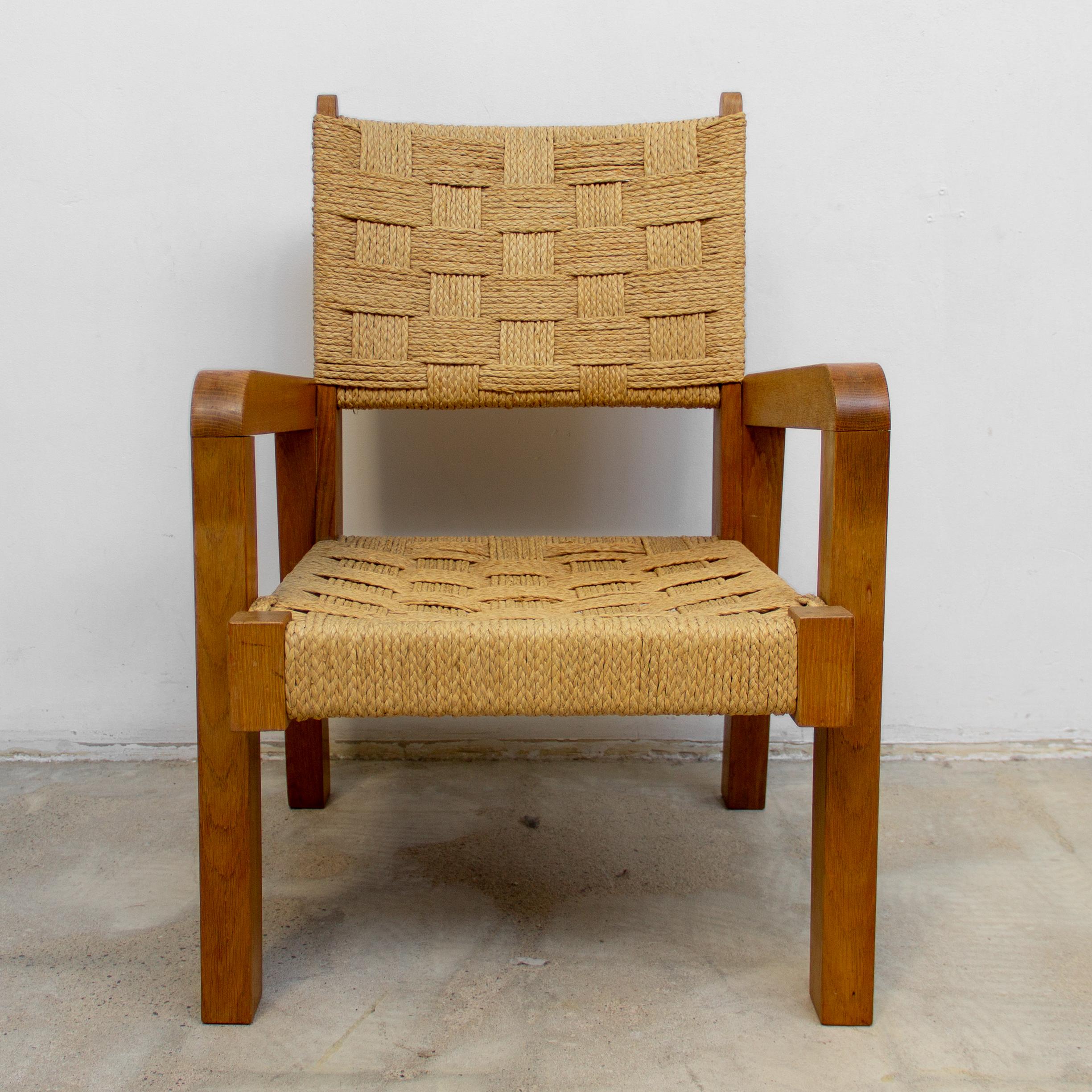 Rare modernist bold oakwood lounge chair and handcrafted raffia woven seating and backing. This bold shaped modernist lounge chair is executed in oakwood and wreath raffia weaving. Materials raffia and stained oak. The raffia wreath seat and