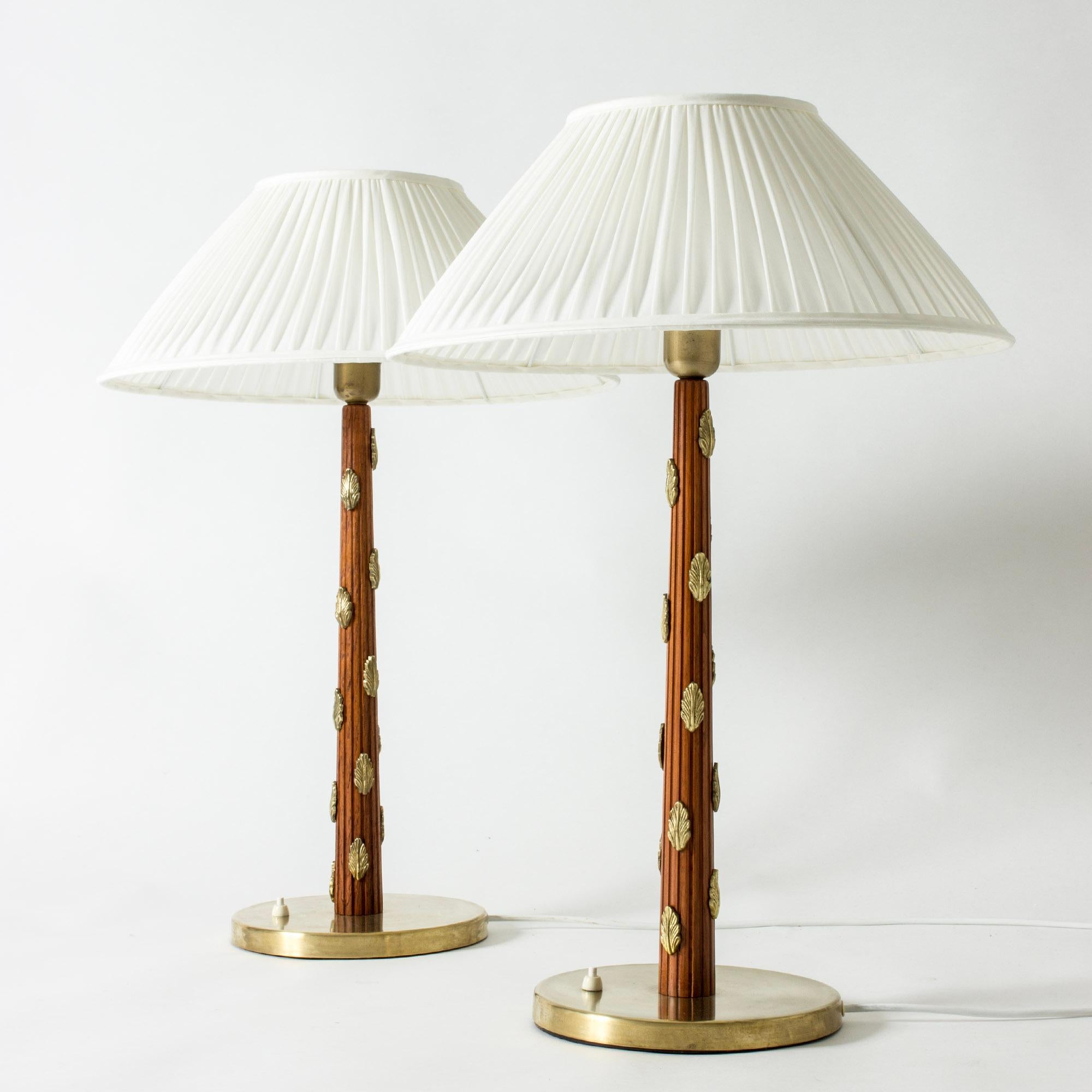 Pair of stunning oversized table lamps by Hans Bergström, made in the late 1930s. Mahogany stems embossed with stripes and decorated with beautiful appliquéd brass leaves. Pleated shades.

Hans Bergström was the owner and creative director of the
