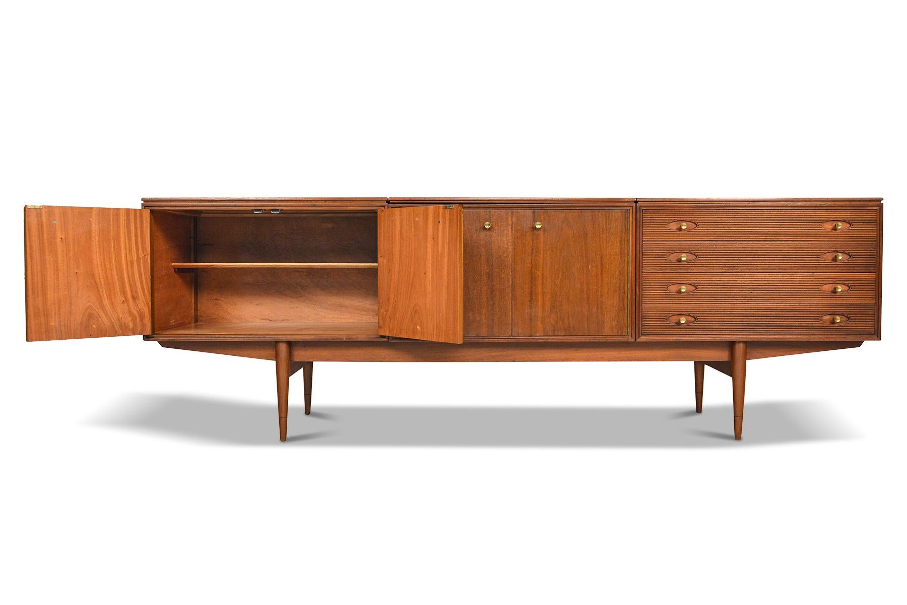 This long English modern credenza was designed by Robert Heritage for Archie Shine Furniture in 1957. Known as the “Hamilton” model, this beautiful piece is cased in mahogany with a curved lip in the back. An extremely unusual example of this model,