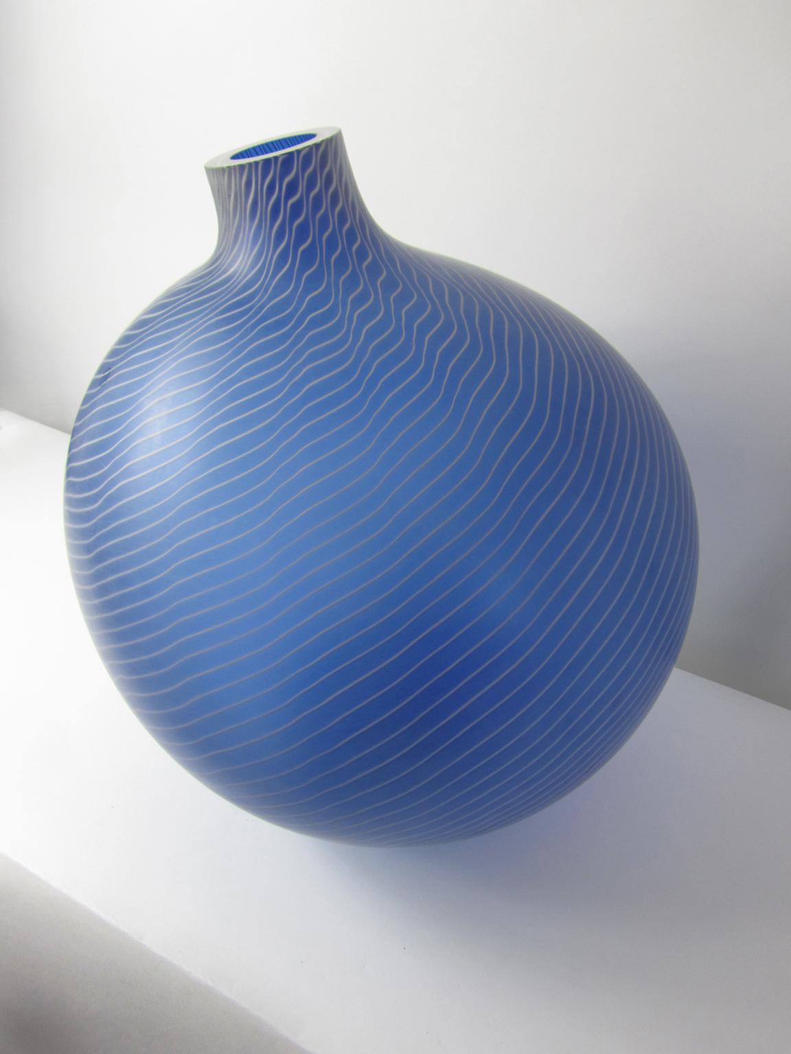This stunning vessel is by Salviati, Its scale makes it most unusual, and the asymmetrical ovoid shape adds to its unique beauty. The exterior is a matte sapphire blue with ultra thin white canes that swirl around the entire shape. This vessel is
