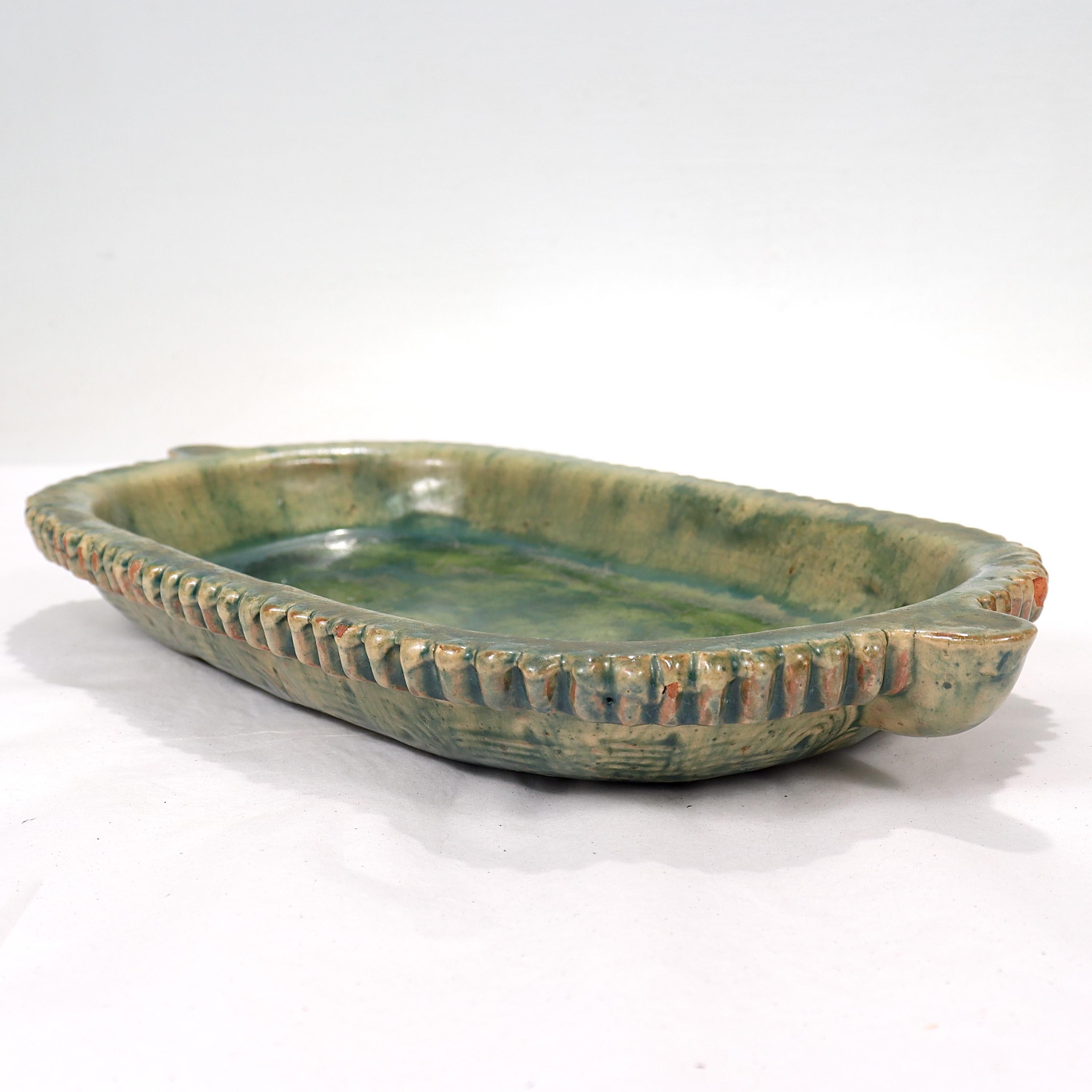 Fino y raro cuenco bajo o plato oblongo de cerámica americana Arts & Crafts.

En forma de cuenco o plato alargado y oblongo, con asas salientes en los extremos. Hay craquelado por todas partes, lo que le da un aspecto envejecido.

La parte