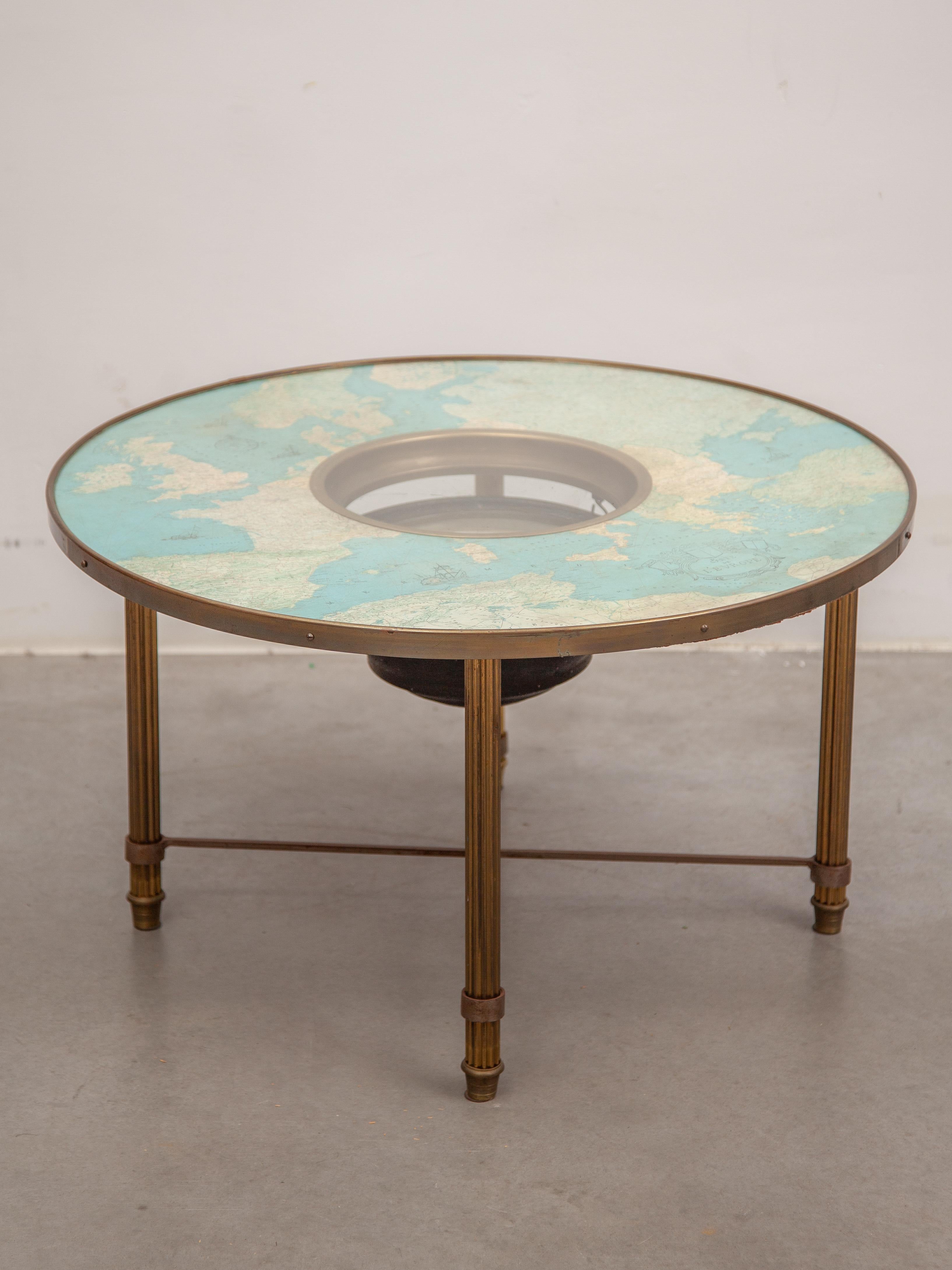 A rare decorative French coffee table with a cosmographic map under a glass top with a functional compass positioned in the middle. Supported by a round brass frame with four legs connected by stretchers. Circa 1950. In original good condition.