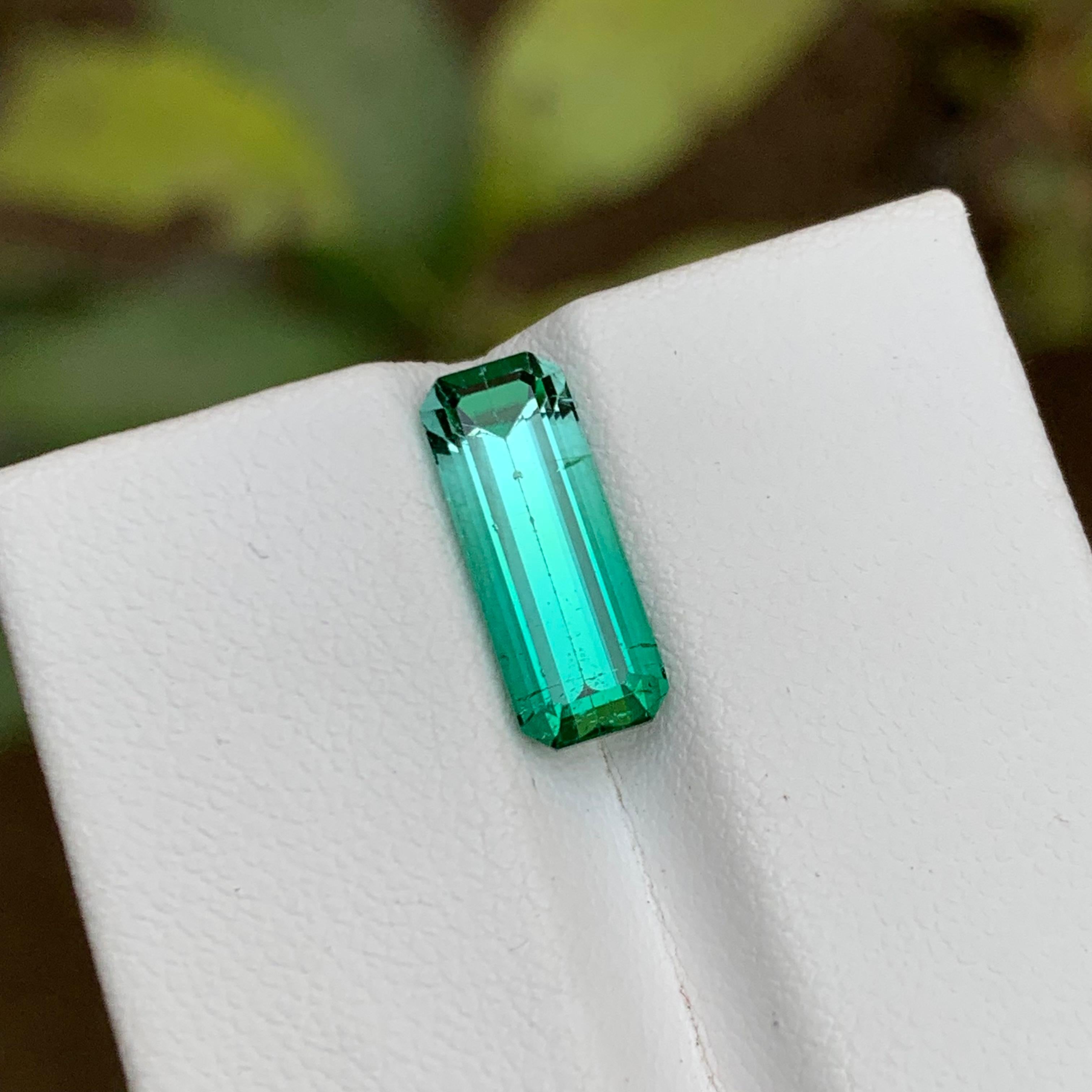 GEMSTONE TYPE: Tourmaline
PIECE(S): 1
WEIGHT: 3.25 Carats
SHAPE: Step Emerald
SIZE (MM):  13.62 x 5.25 x 5.01
COLOR: Neon Bluish Green Bicolor
CLARITY: Approx 90% Eye Clean
TREATMENT: None
ORIGIN: Afghanistan
CERTIFICATE: On demand

This dazzling